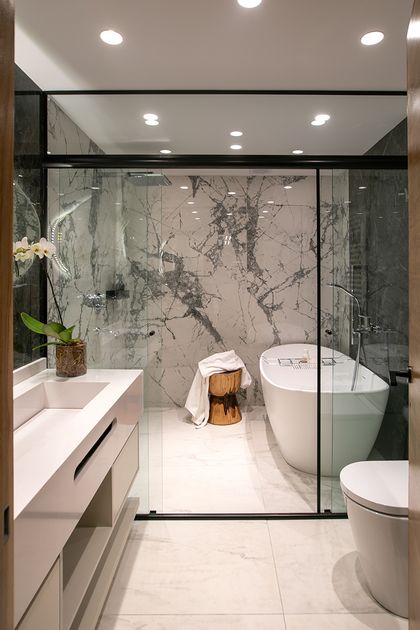 Baño moderno con mármol, bañera blanca y mampara vidrio — proyecto Casa Oroño, por Estudio Plats, en Buenos Aires