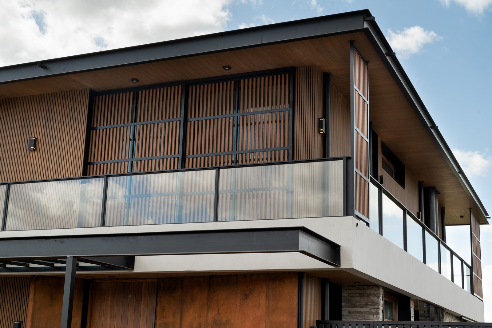 Fachada moderna de casa con revestimiento de madera y amplios ventanales — proyecto Obra Casa Pilará, por lifecycle, en Pilar