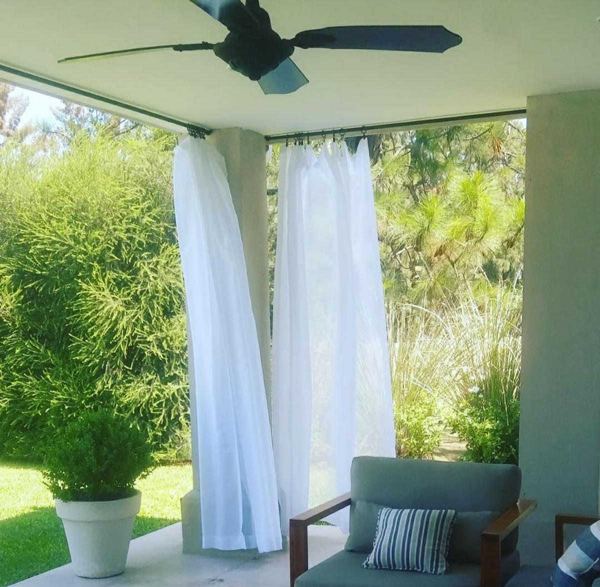Pátio moderno com cortinas brancas e vegetação exuberante — projeto Caning, por Decortinasytelas, em Buenos Aires