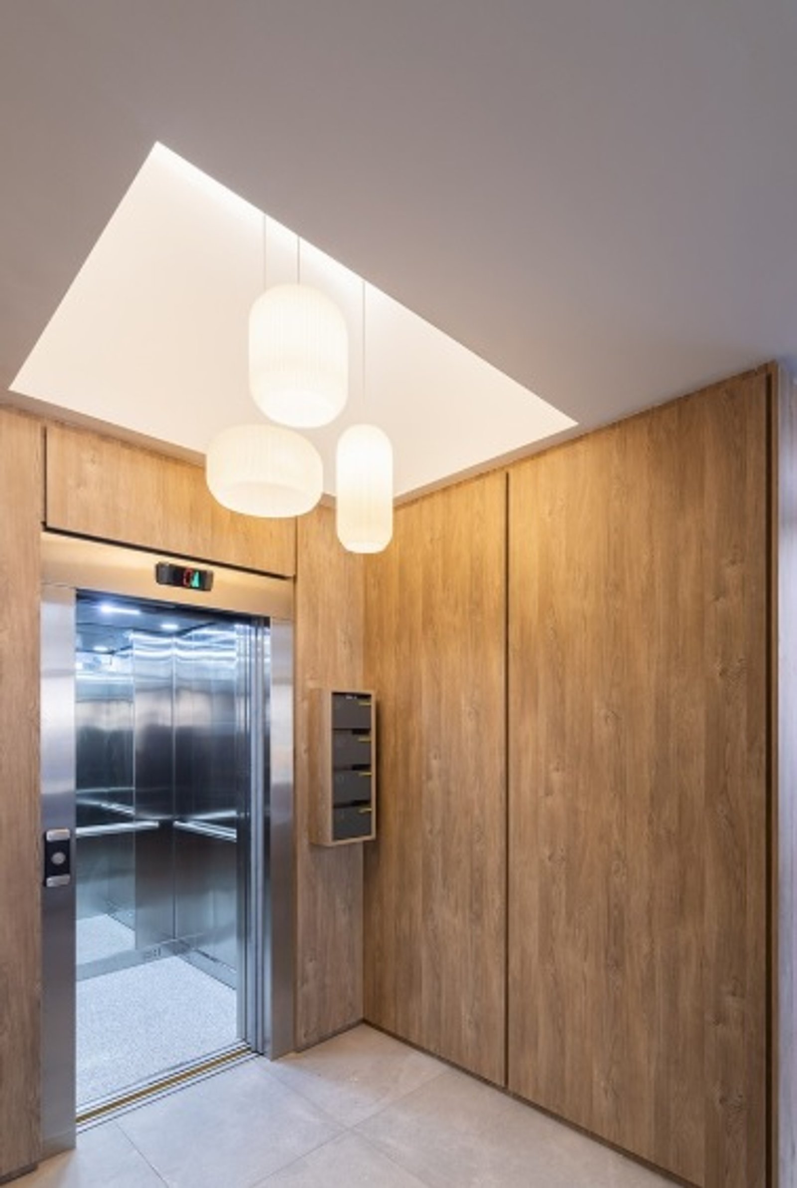 Pasillo moderno con ascensor, revestimiento en madera y luz cenital — proyecto EDIFICIO PATRIMONIO, por DIB OBRIST Arquitectas, en Rosario