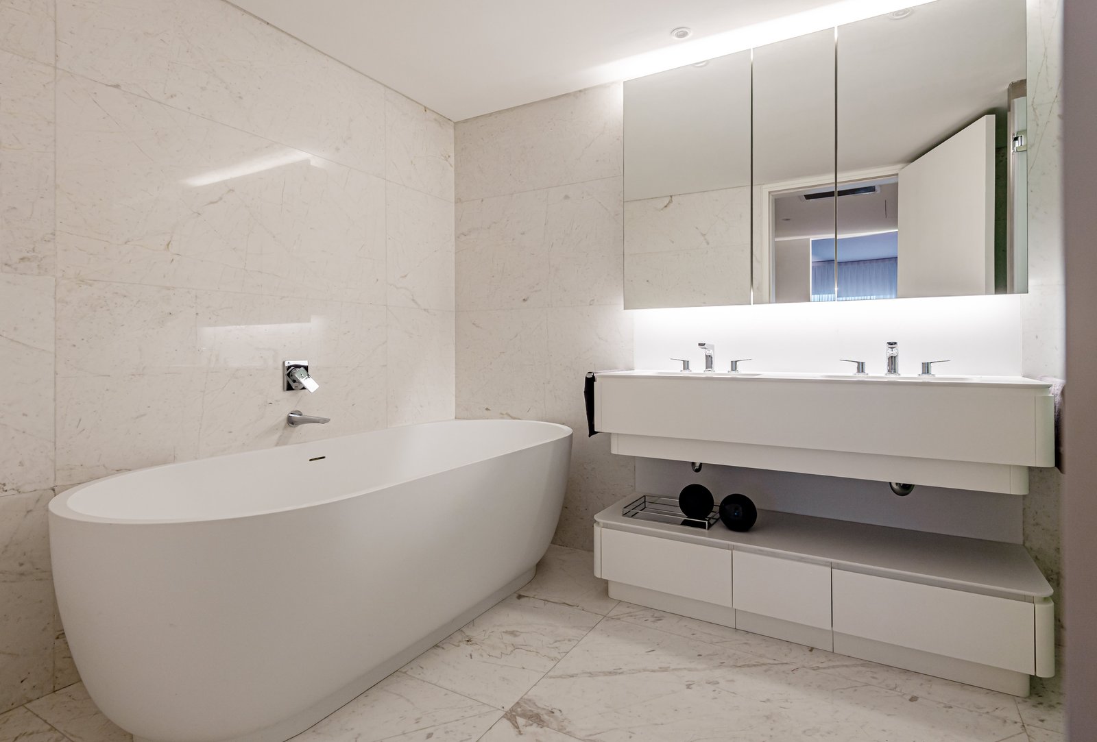 Banheiro moderno minimalista com banheira de imersão branca e revestimentos de mármore — projeto OBRA OCEANA, PUERTO MADERO, por MARCELO MAZZA, em Puerto Madero