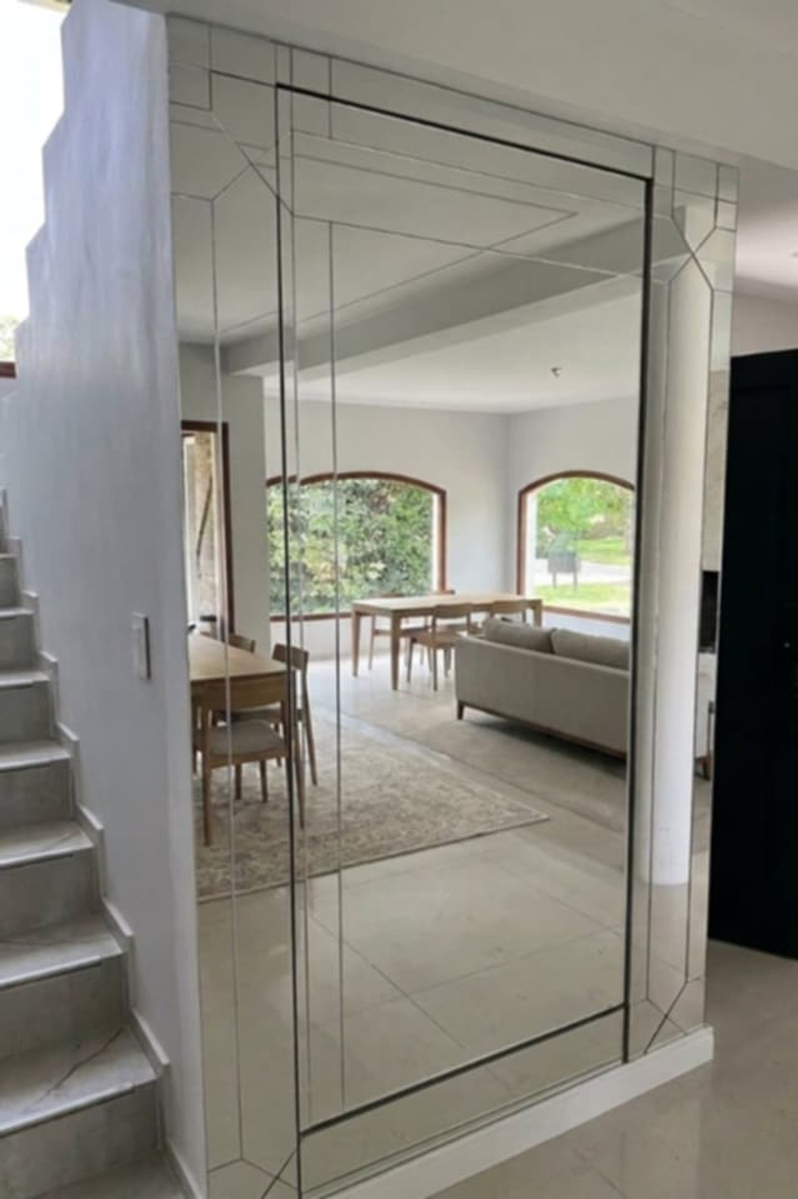 Interior moderno com parede espelhada geométrica e escada flutuante — projeto Puerta Oculta Integrada en Revestimiento de Espejos Repartidos, por Vic Vitrum, em Neuquén