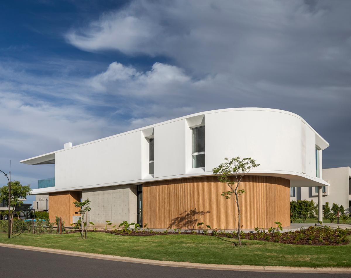 Fachada moderna com paredes curvas e revestimento de madeira — projeto Casa Didney, por Jorgelina Tortorici & asoc., em Nordelta