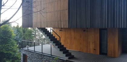 fachada moderna con revestimiento de madera y escaleras exteriores — proyecto Casa Península San Pedro, por Servente Larrazabal Arq, en Bariloche