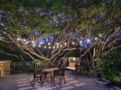 Patio nocturno con árboles iluminados y muebles de diseño — proyecto Los pasos de Justina. Club de Campo El TIPAL, por Marina Caballer