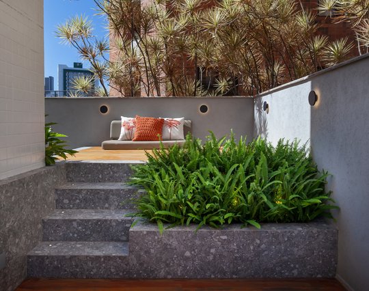 Terraza con vegetación, deck de madera y banco gris moderno — proyecto APARTAMENTO TP, por Frederico Bicalho Arquitetura