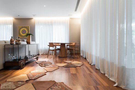 Living contemporáneo con piso de madera, cortinas blancas y mobiliario de diseño — proyecto Projeto MT Ipês, por Marta Calasans
