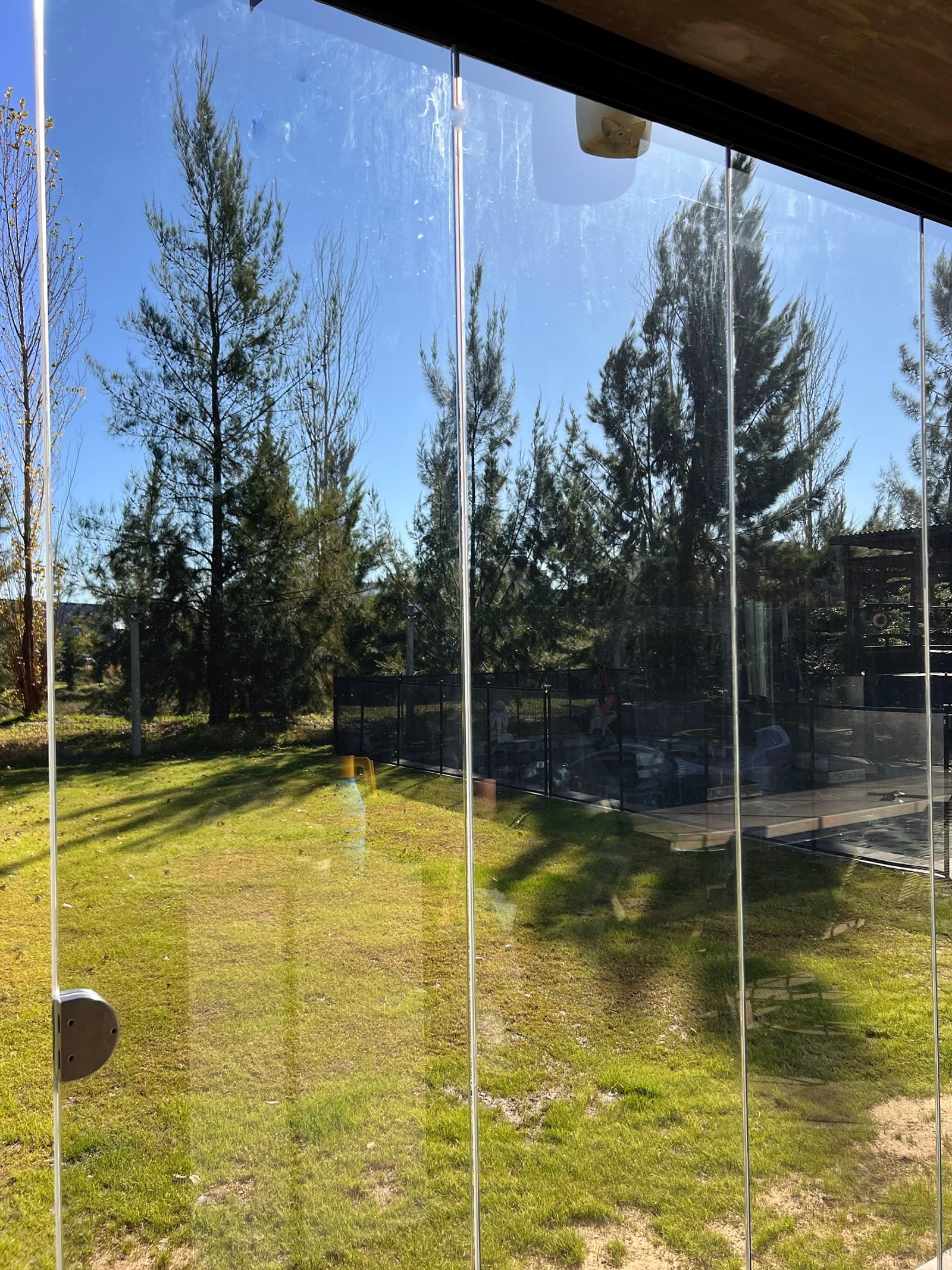Jardín con cerramiento de vidrio y césped bien cuidado — proyecto FILMS 3M de control Solar, Seguridad y Privacidad, por Grupo Laminar 