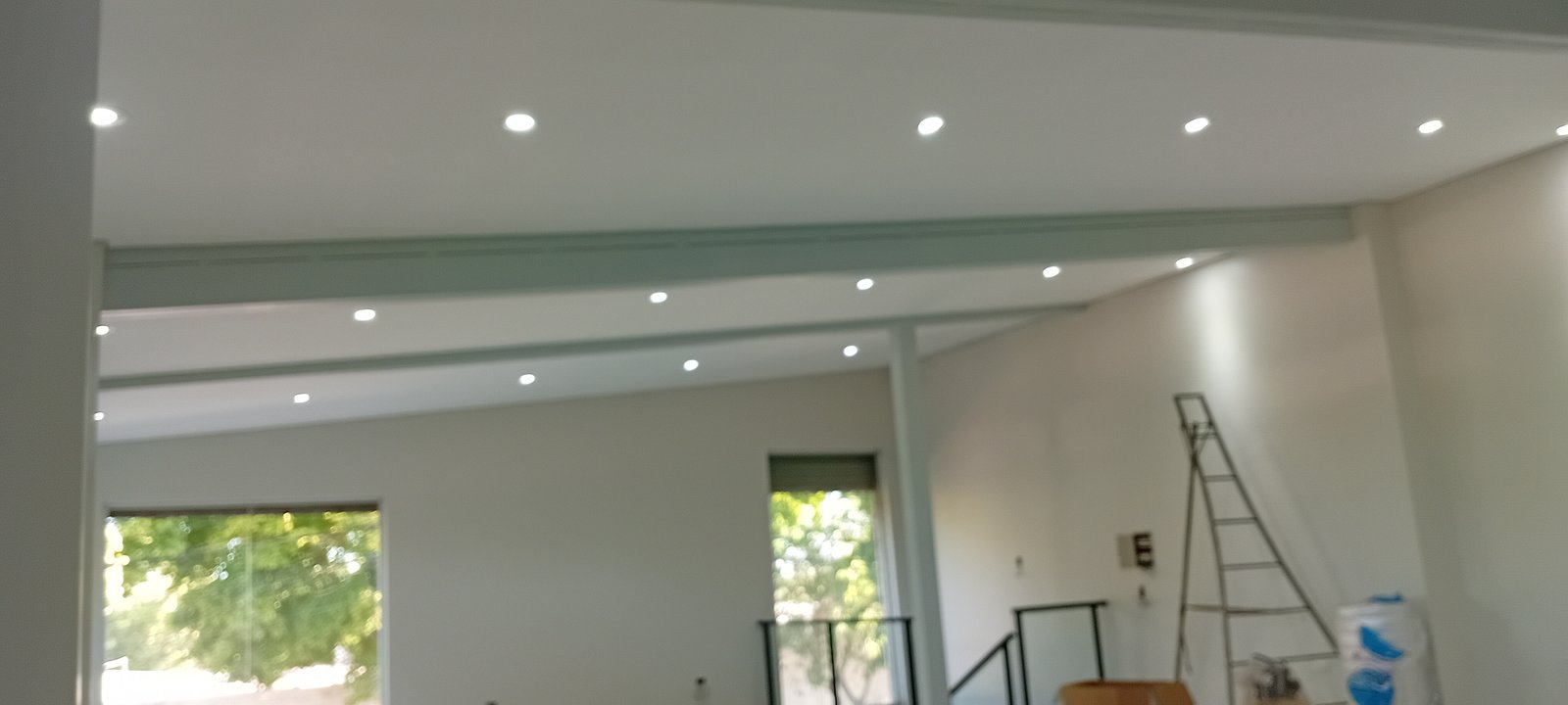 Espacio interior en construcción con vigas expuestas y luces empotradas — proyecto MITRE SANITARIOS, por Yamil Cerna, en Tunuyán