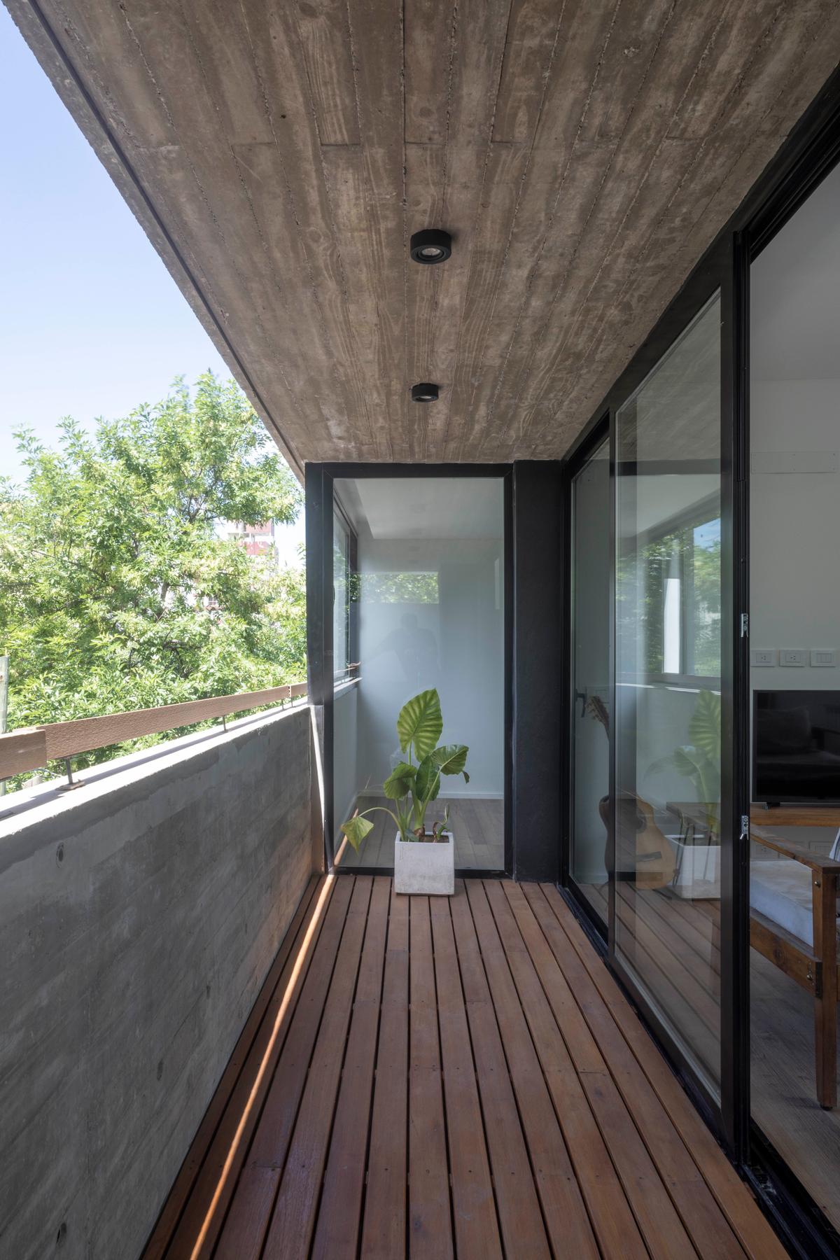 Varanda moderna com teto de concreto aparente e deck de madeira — projeto Terrazas de Saavedra, por DREI Arquitectura y Desarrollos, em La Plata