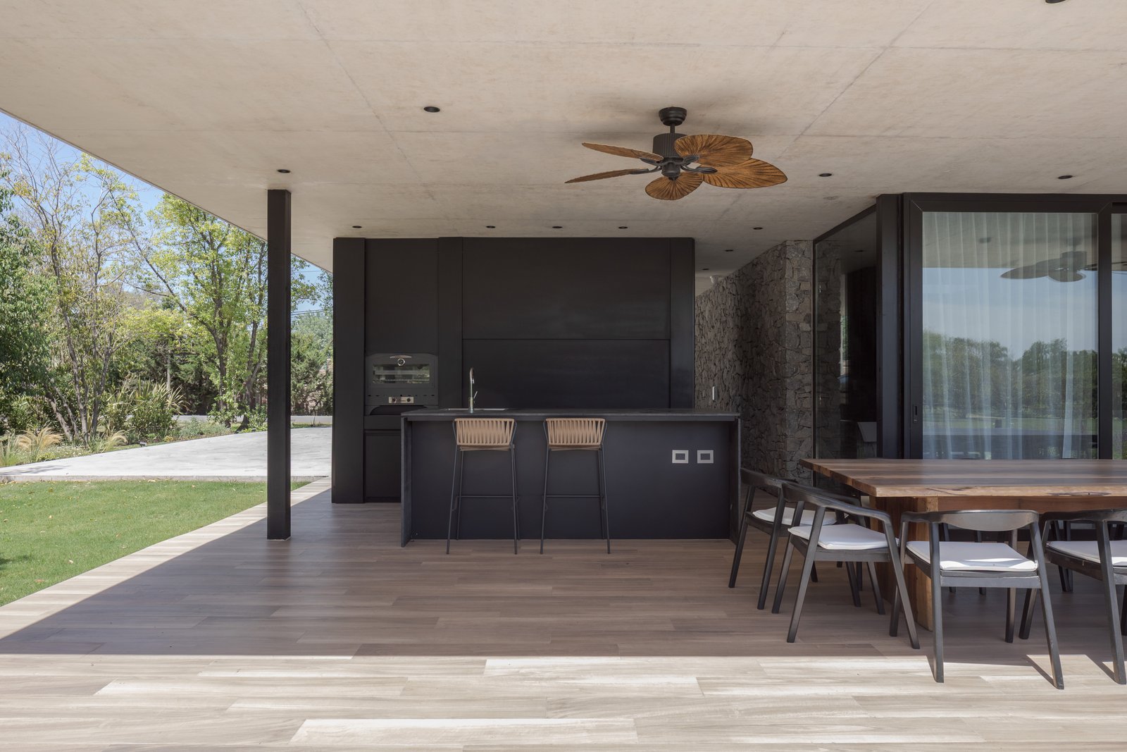 Cozinha externa moderna com ilha e deck de madeira — projeto Casa PLANALTO, por Grupo CRBN, em Av. Pres. Perón 10298