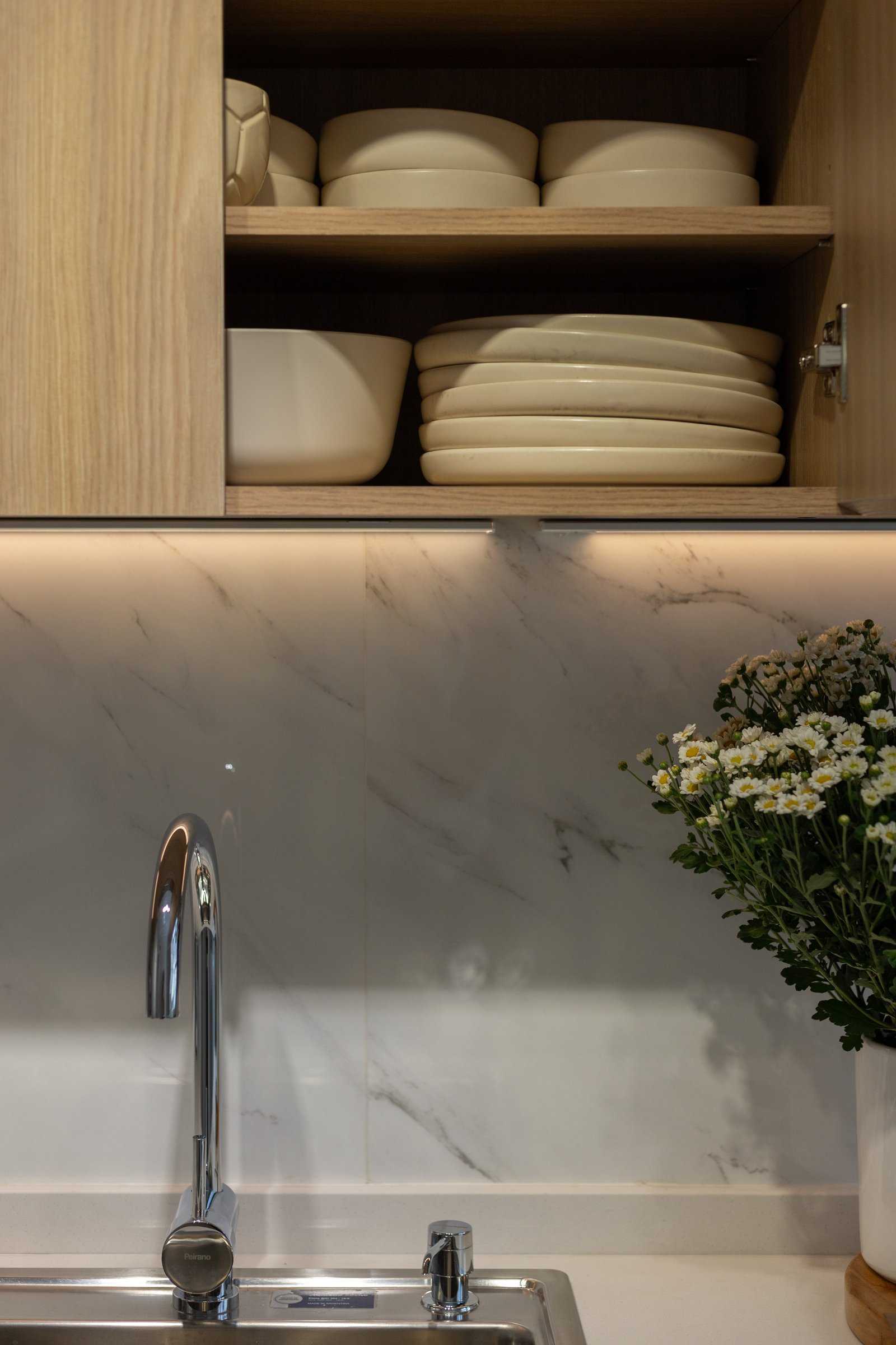 Cocina moderna con muebles de madera clara y luz indirecta — proyecto Gascón, por Martina Kleinert, en Caballito