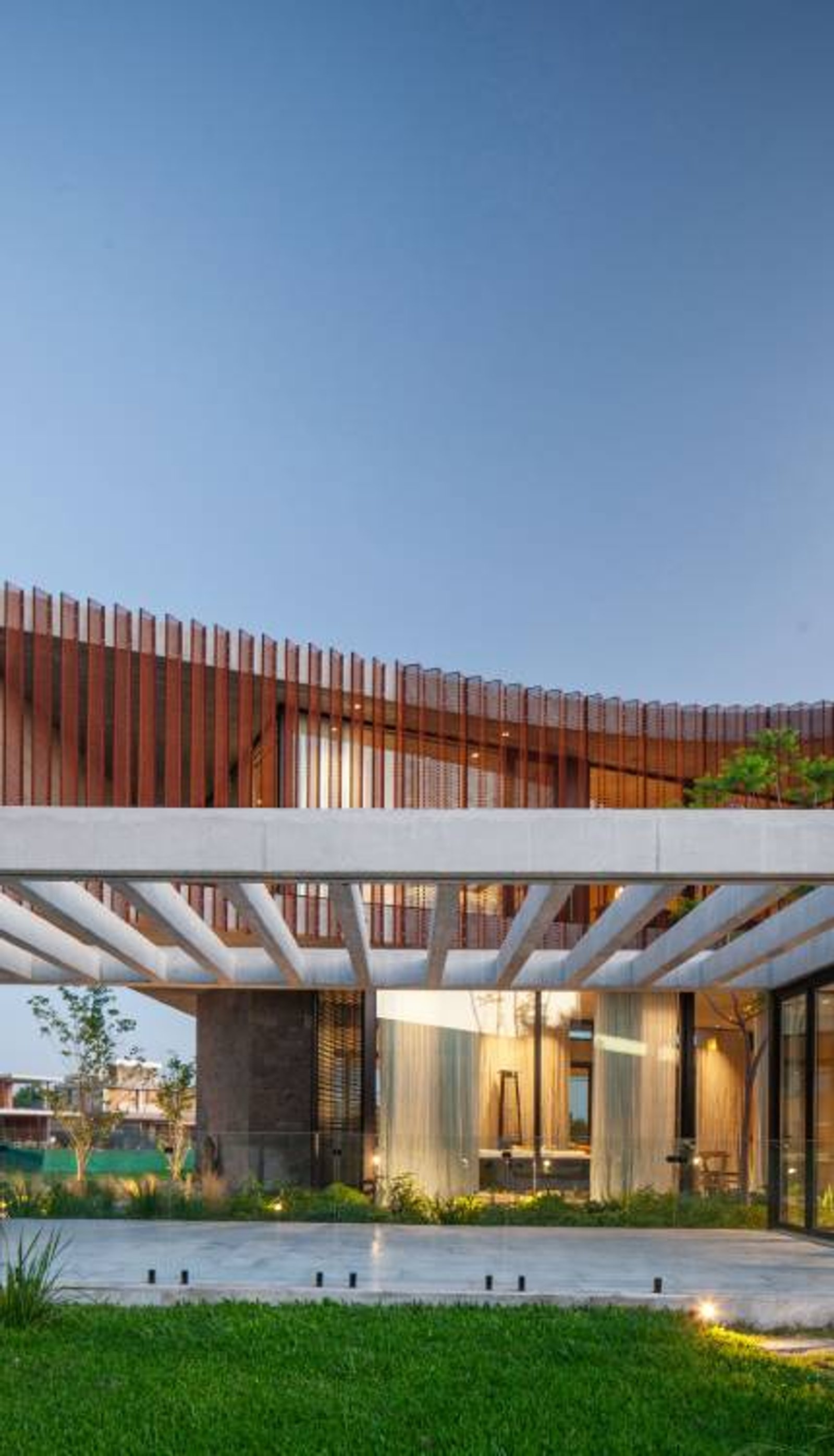 Fachada moderna con pérgola de hormigón y revestimiento curvo de madera — proyecto Casa Órbita, por Estudio PK, en Nordelta