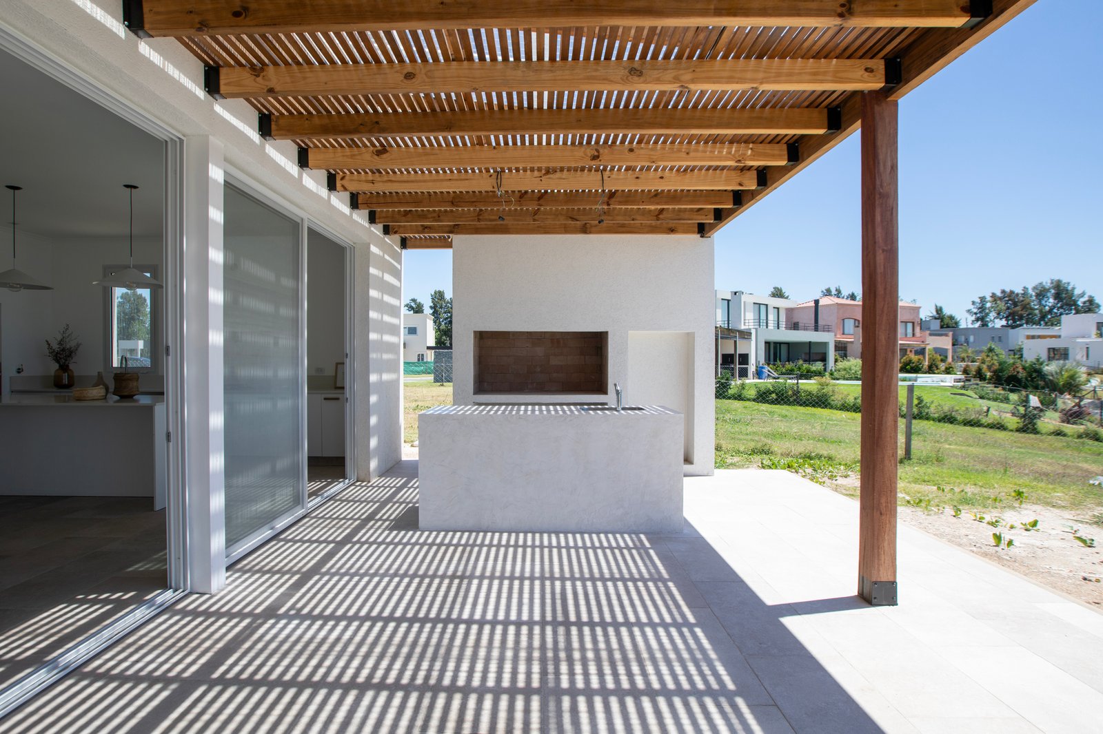 Área de churrasco moderna com pergolado de madeira e sombra — projeto OBRA LE PIETRE DEL CASALE SABBIA, por ILVA, em Provincia de Buenos Aires