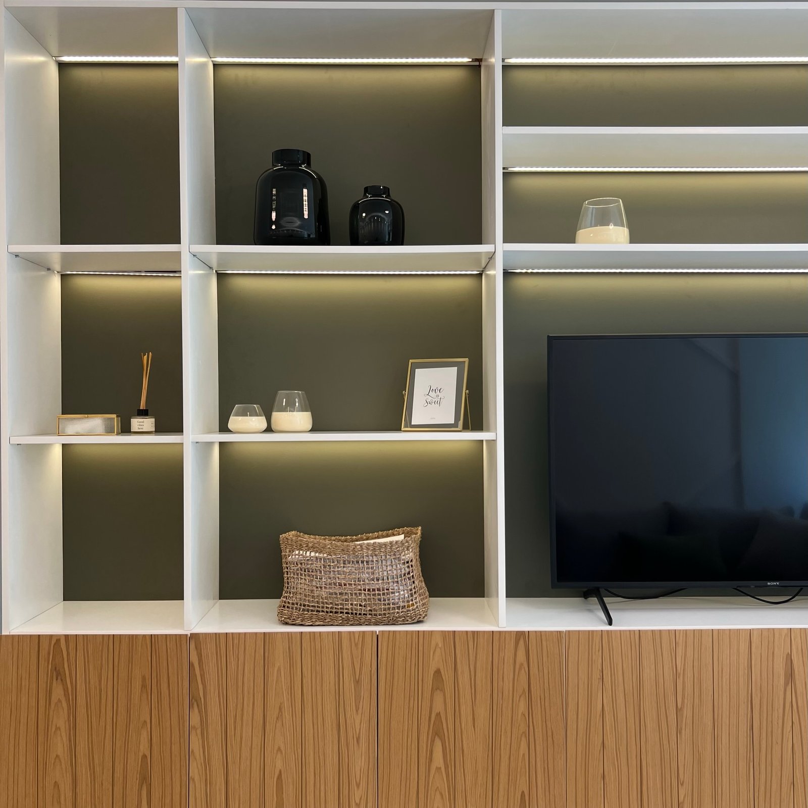 Estantería empotrada moderna con iluminación indirecta y panelado de madera — proyecto Basualdo II, por MDBK Arquitectura, en Liniers