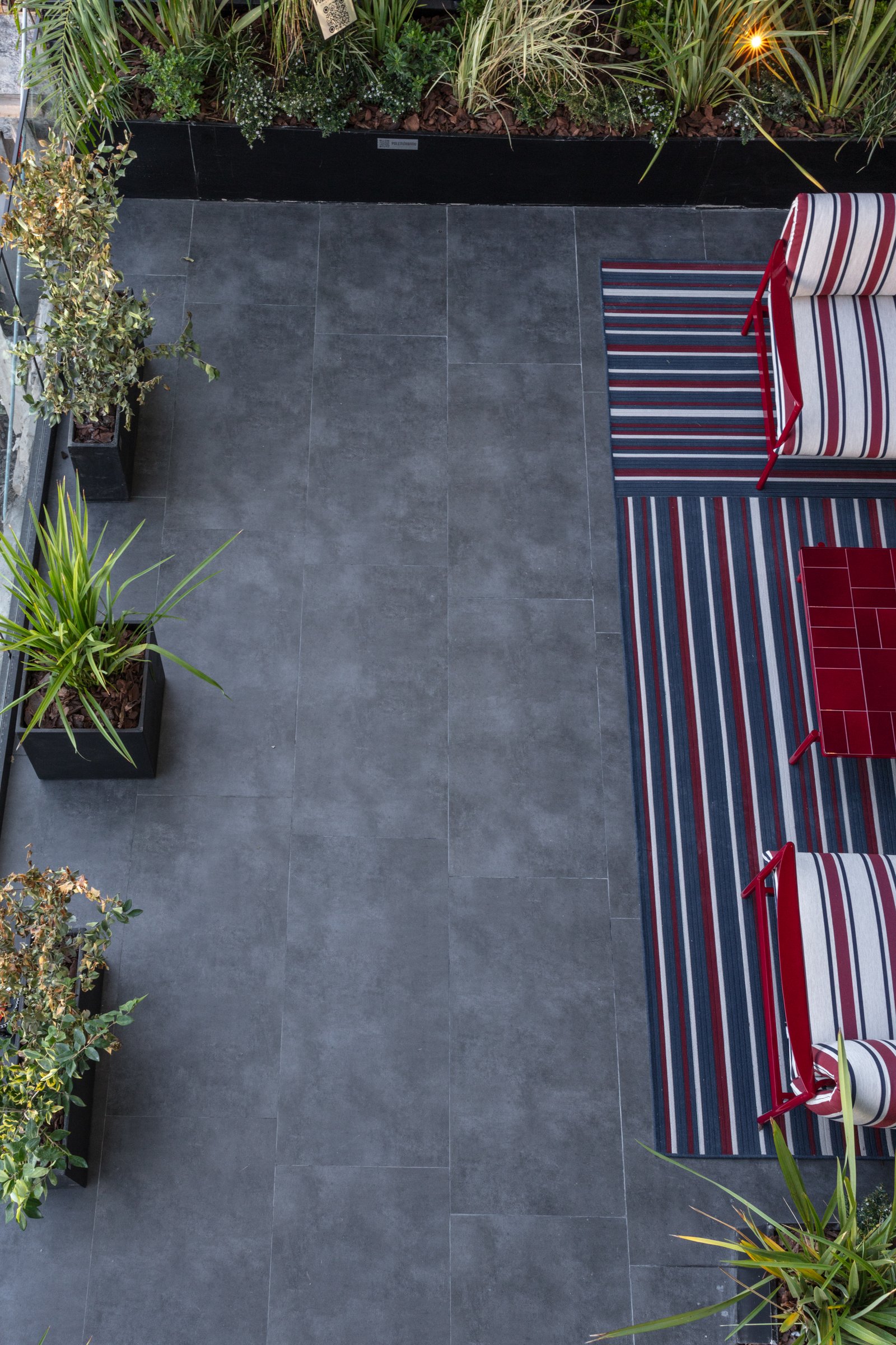Patio moderno con sillones rayados y suelo de baldosas grises — proyecto Pia Magri, por San Lorenzo Design, en Cam. de los Remeros 1585