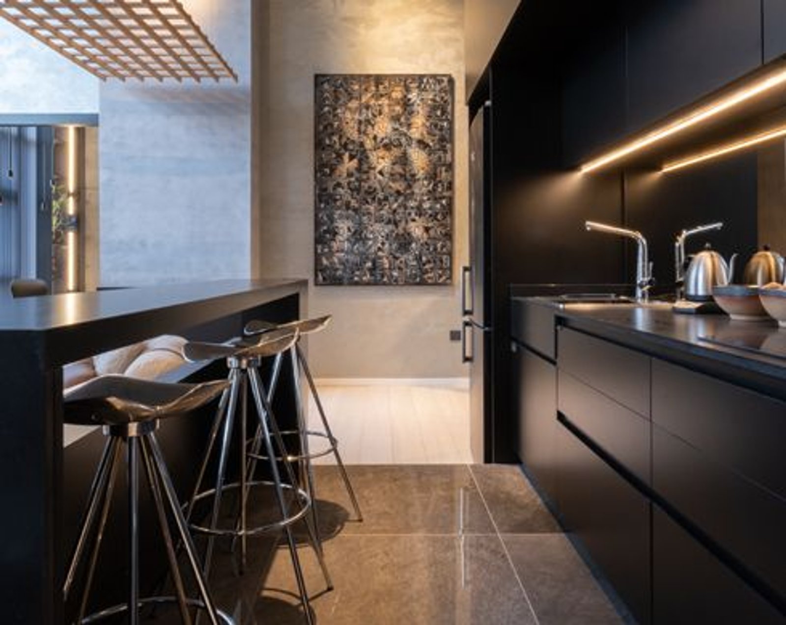 Cozinha moderna com ilha, arte abstrata e detalhes em madeira preta — projeto Casa Foa Córdoba 2025, por Vite Porcellanato, em Ciudad de Córdoba