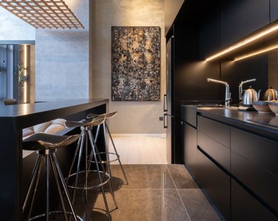 Cocina moderna con isla, arte abstracto y detalles en madera negra — proyecto Casa Foa Córdoba 2025, por Vite Porcellanato, en Ciudad de Córdoba