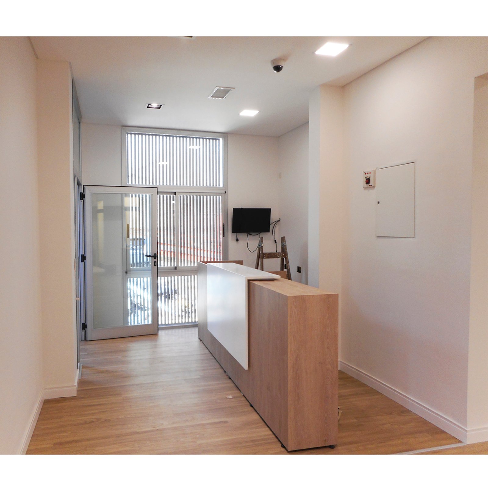 Recepción comercial moderna con escritorio de madera y blanco — proyecto Oficinas CO, por ASIA - arquitectura, en Villa Santa Rita