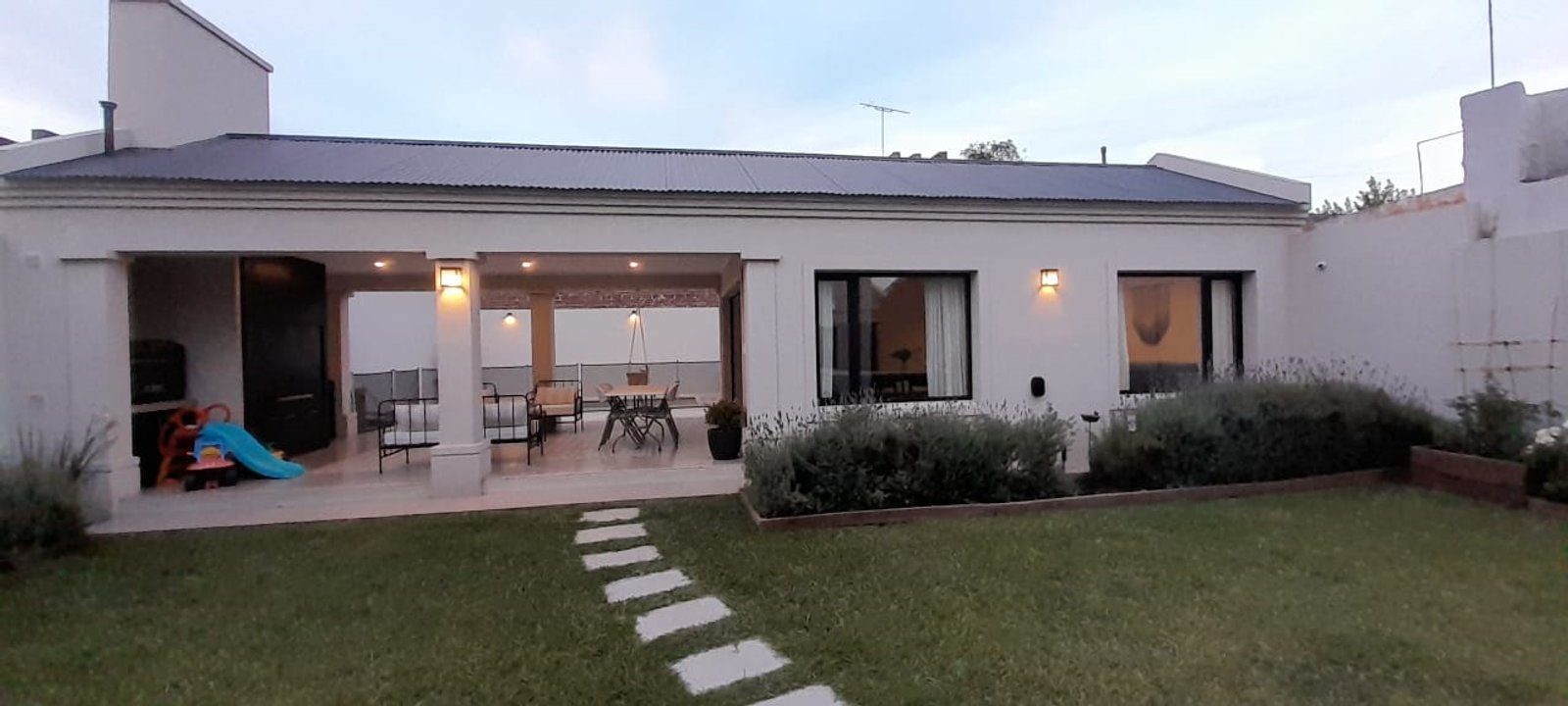 Fachada moderna con patio cubierto y césped cuidado — proyecto Casa FF, por Forma, en Balcarce