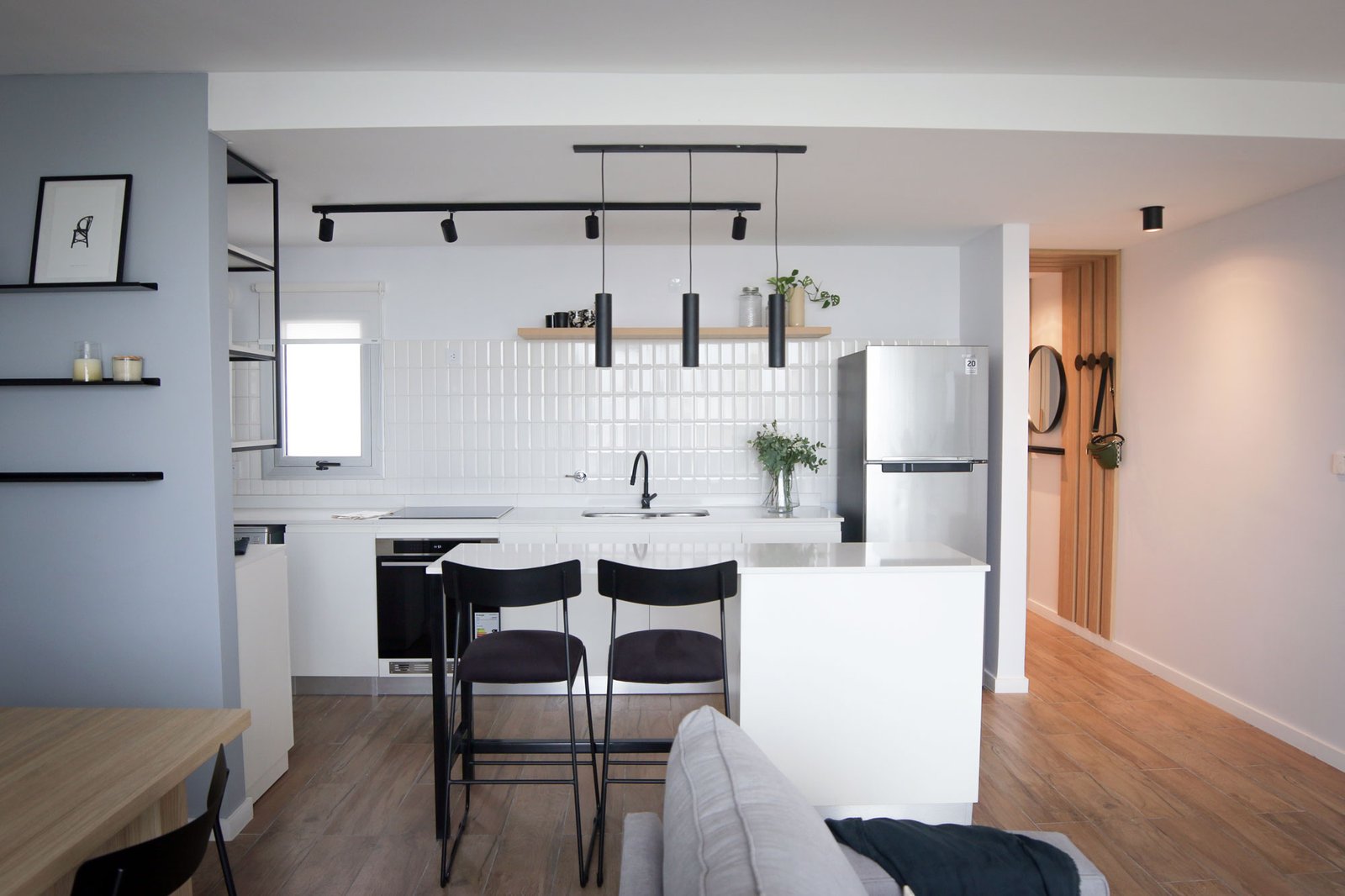 Cocina y living moderno, minimalista, con isla blanca y detalles negros — proyecto Departamento Airbnb, por Jeitinho Estudió Creativo, en La Plata