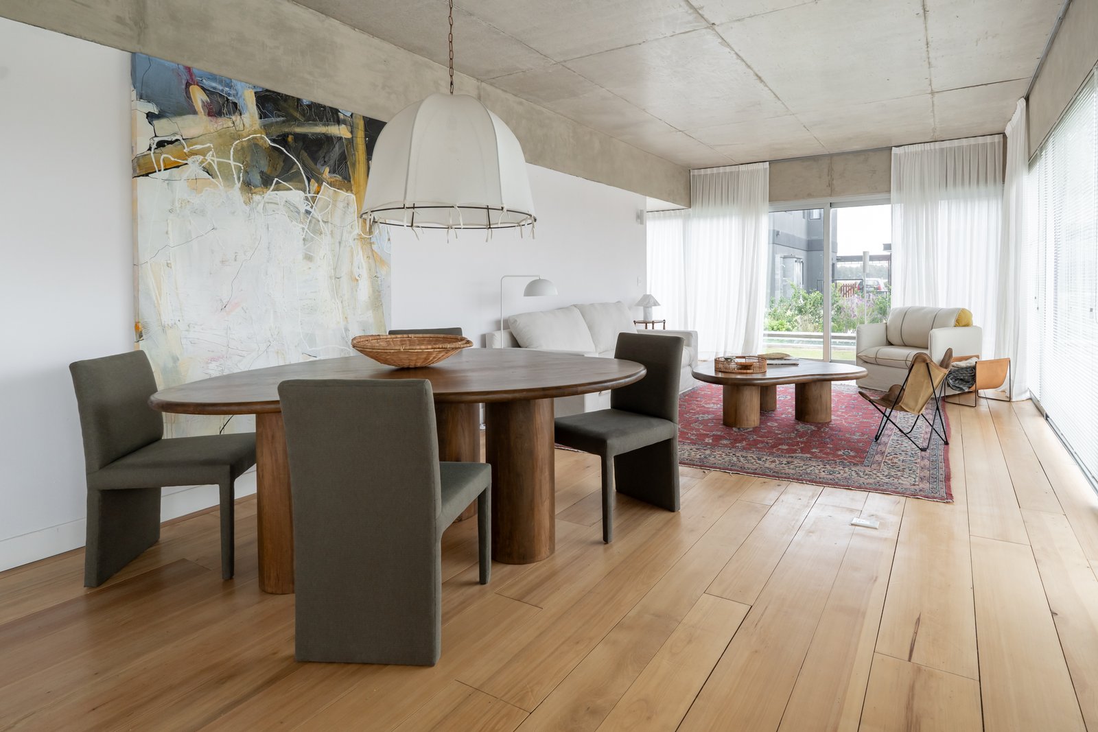 Sala de jantar moderna com mesa oval de madeira e cadeiras cinzas — projeto Carpinchos, por LACROZE DESIGN STUDIO, em Nordelta