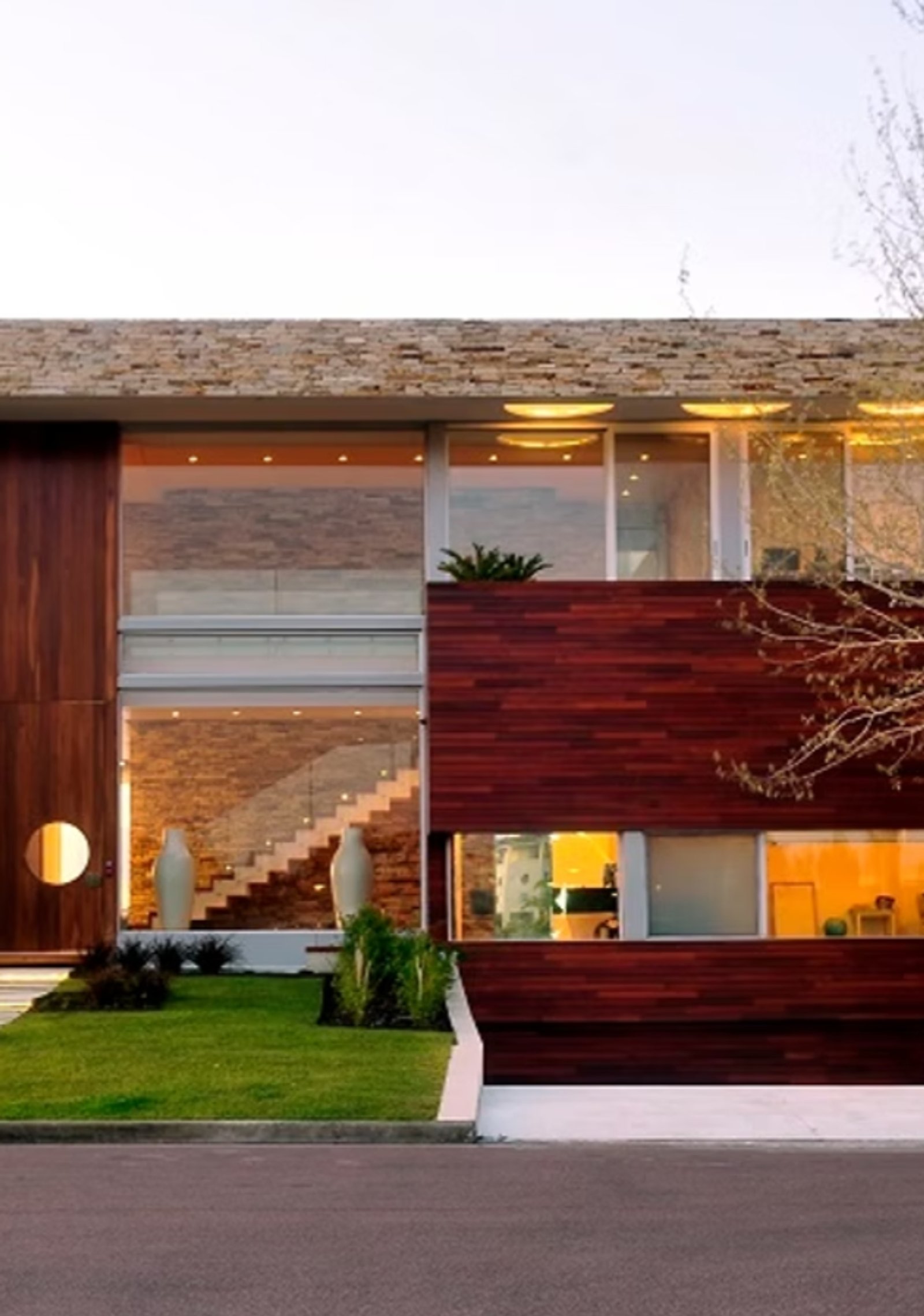 Fachada moderna de madeira escura e pedra com grandes janelas — projeto Casa Cinta, por Barrionuevo Arquitects, em B2814 Los Cardales