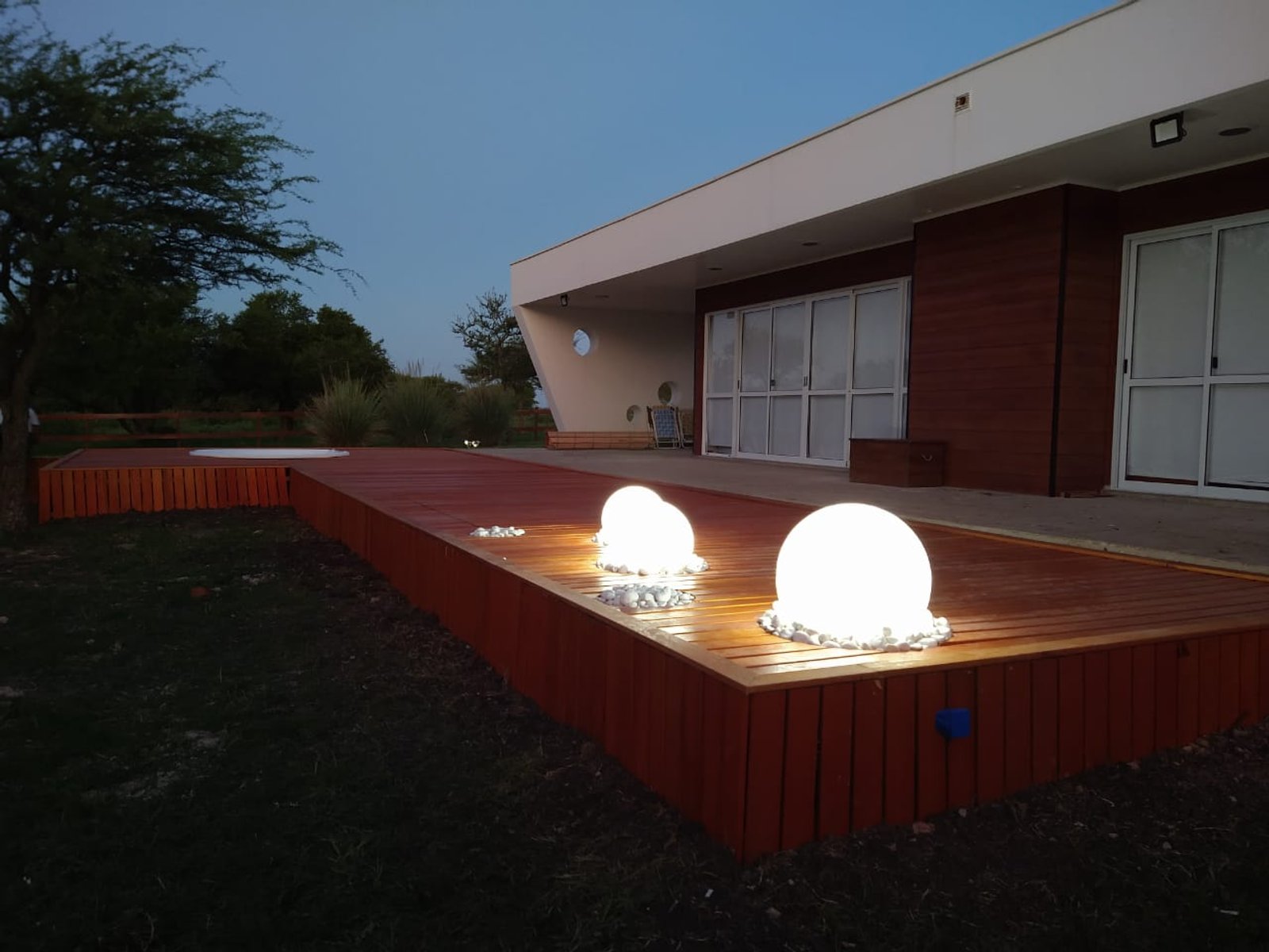 Patio moderno con luces esféricas iluminadas en deck de madera — proyecto Jacuzzi en Deck, por Kardiona, en Villa Elisa