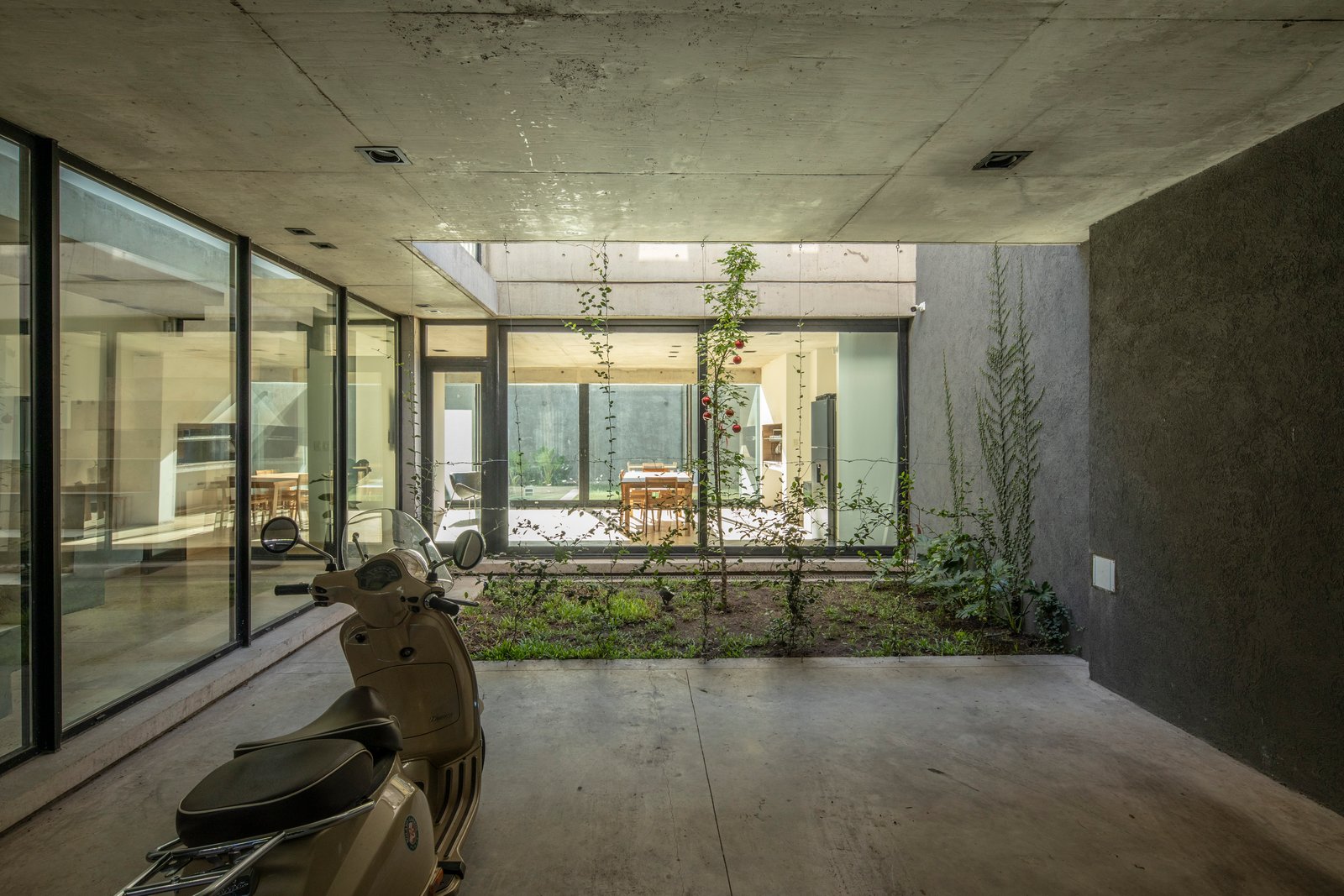 Patio moderno con scooter y estructura de hormigón — proyecto Casa MECHA, por Grupo CRBN, en B1712 Castelar