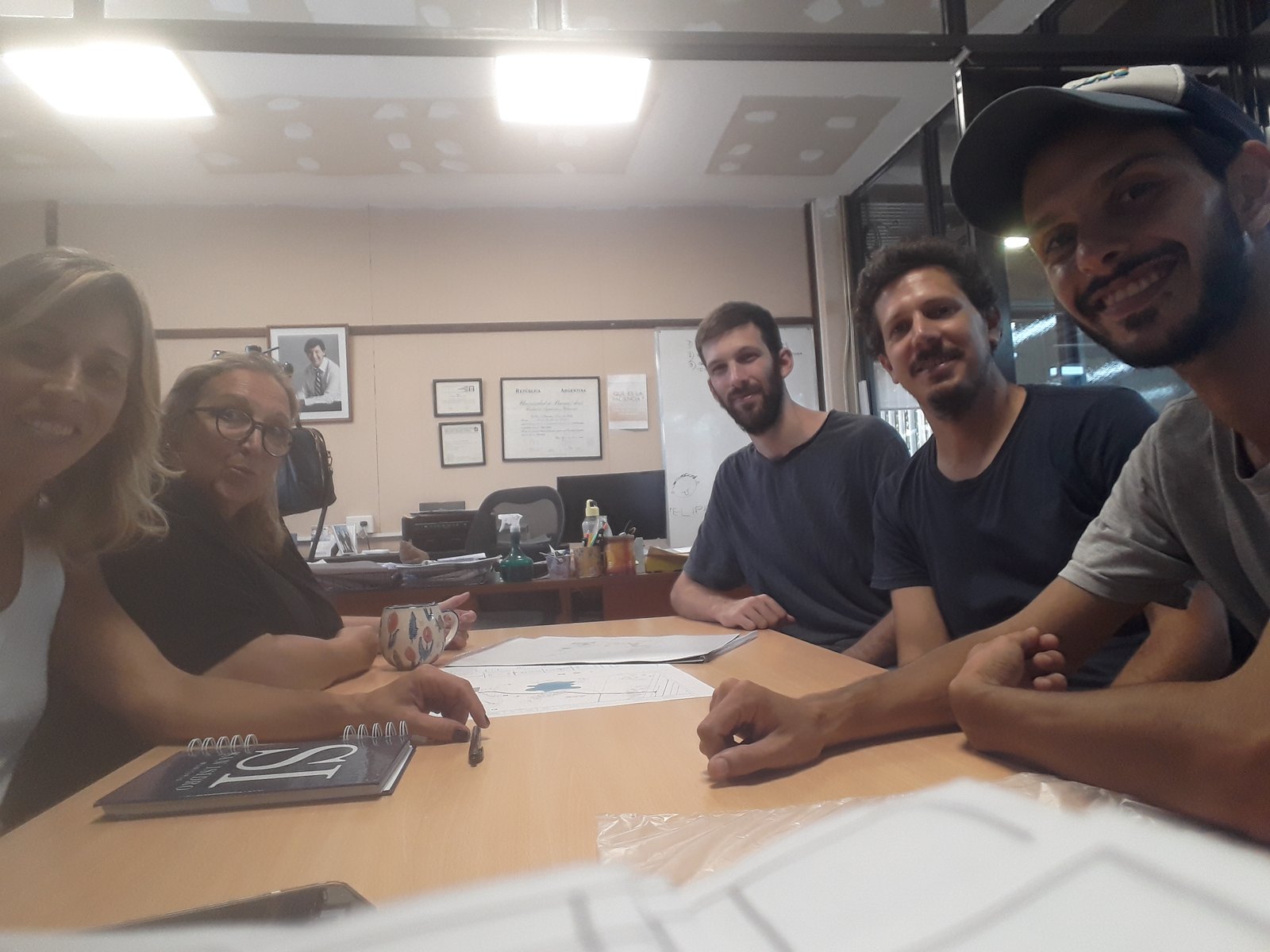 Escritório com mesa de madeira e pessoas reunidas — projeto Parque Público Villa Adelina, por Estudio Rifahi, em B1607 Villa Adelina
