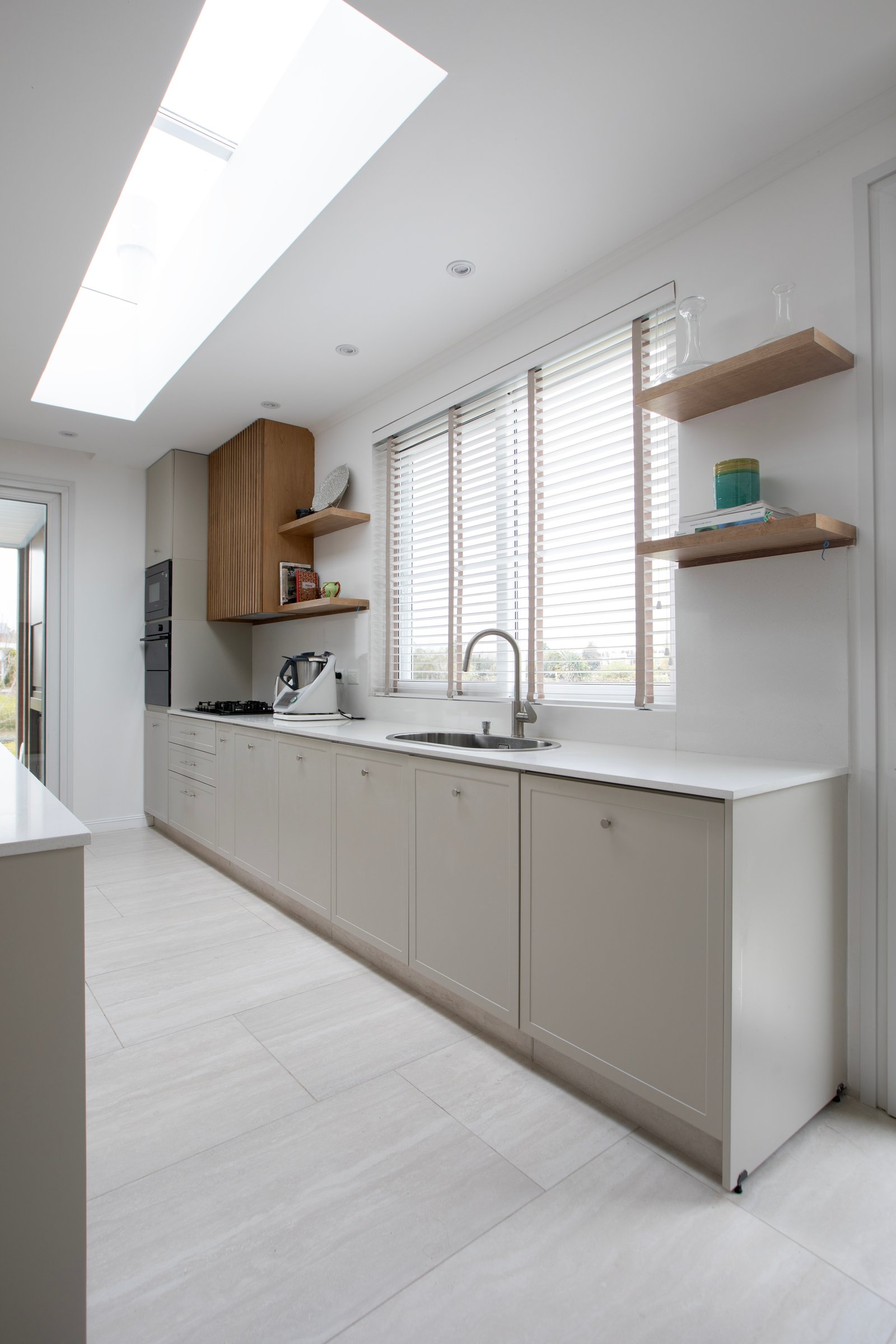Cozinha moderna com claraboia, armários bege e piso de pedra cinza — projeto OBRA EL RETIRO, por ILVA, em Provincia de Buenos Aires