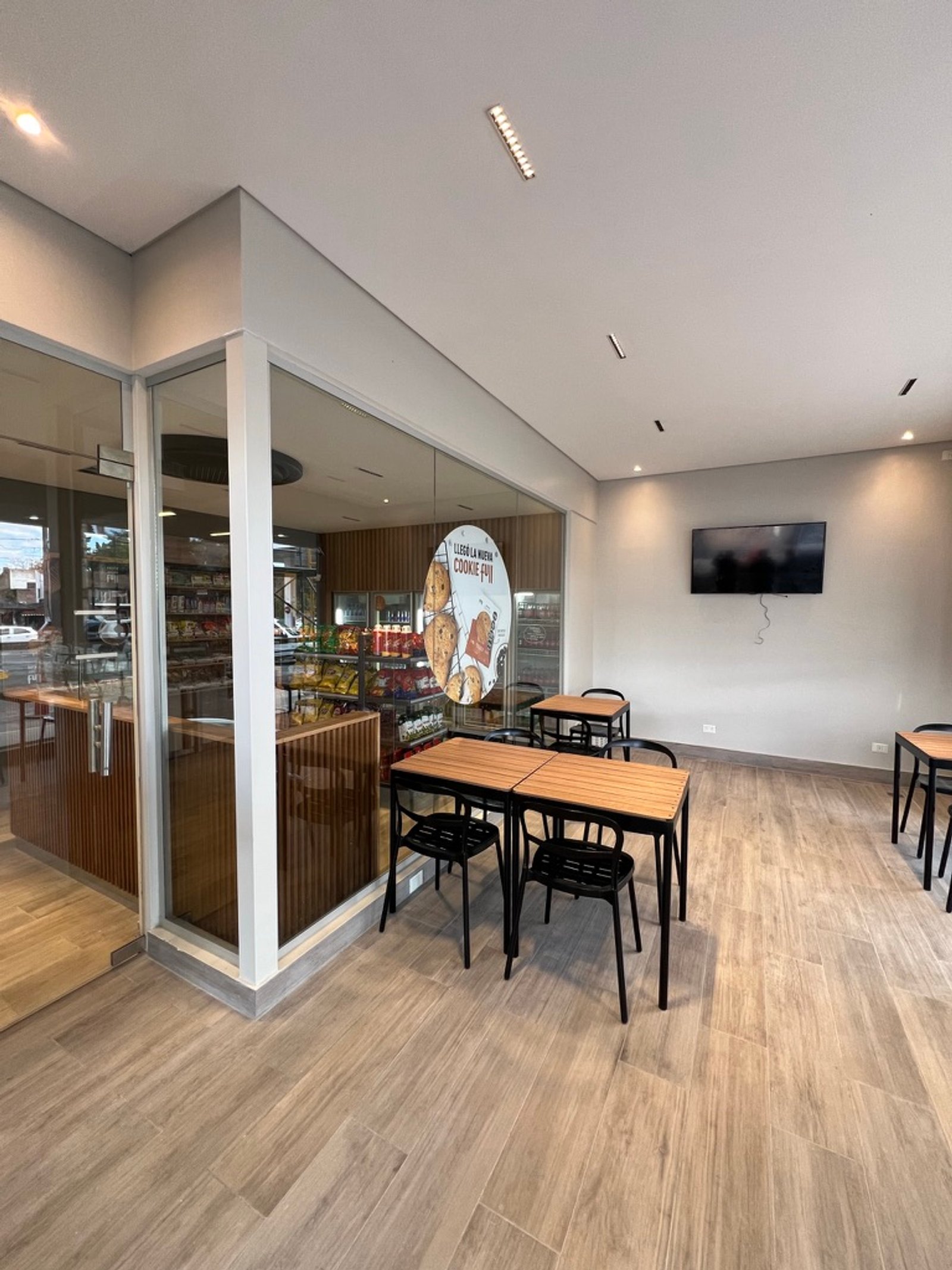 Local comercial moderno con mesas y sillas de metal negro — proyecto Full YPF Muniz, por Arcucci Arquitectura, en Muñiz