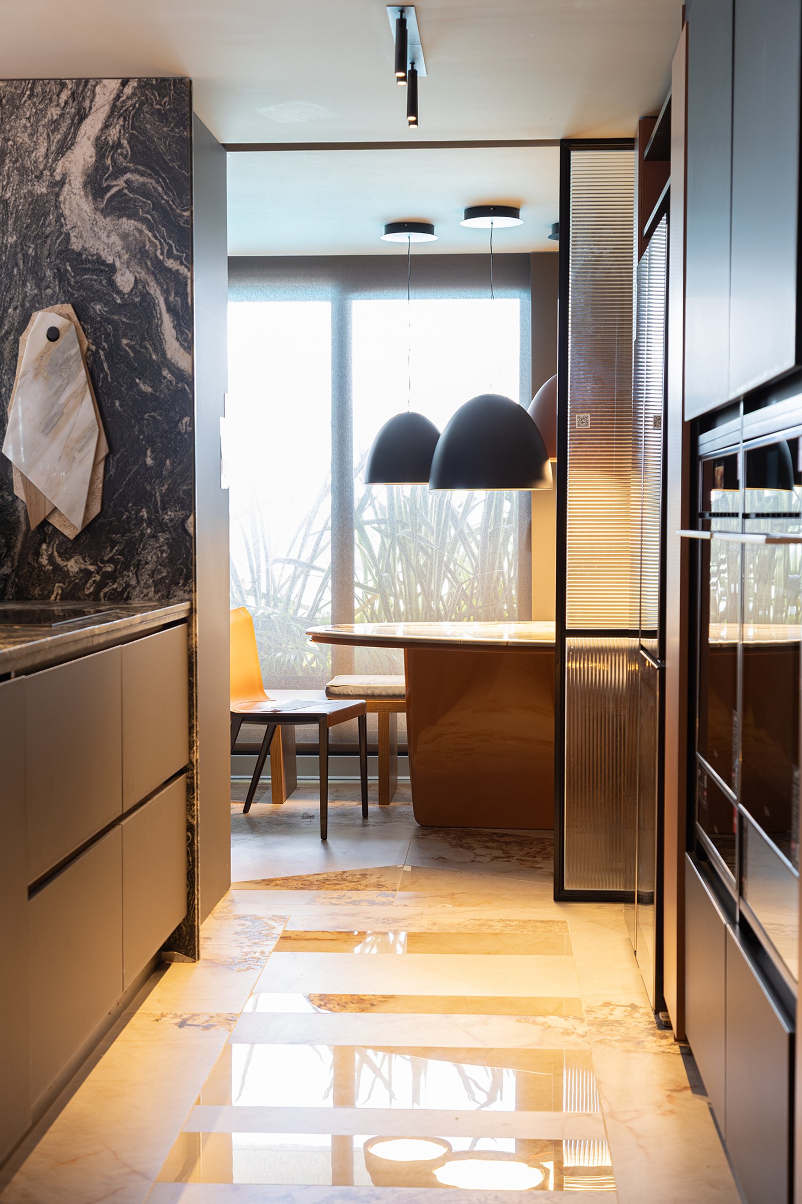 Comedor moderno con pared de mármol, luces colgantes y suelo reflectante — proyecto Adriana Randazzo Arquitectura & Interiorismo, por Gaby Alfonso, en B1648 Tigre