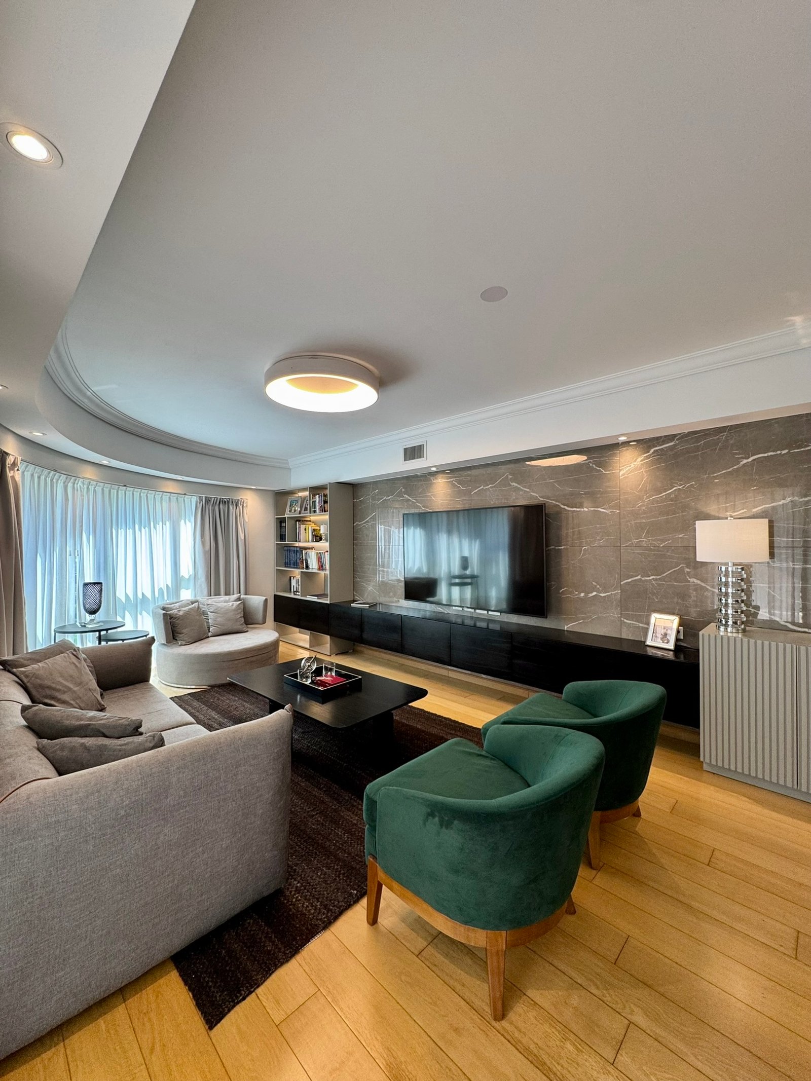 Sala de estar moderna com sofá curvo e poltronas verdes — projeto Olleros, por MDBK Arquitectura, em Belgrano