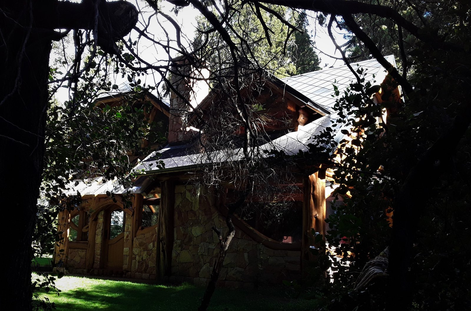 Fachada rústica de madera y piedra en bosque — proyecto Casa Familiar VILLA ARELAUQUEN - SAN CARLOS DE BARILOCHE, por arquiga10573853, en San Carlos de Bariloche