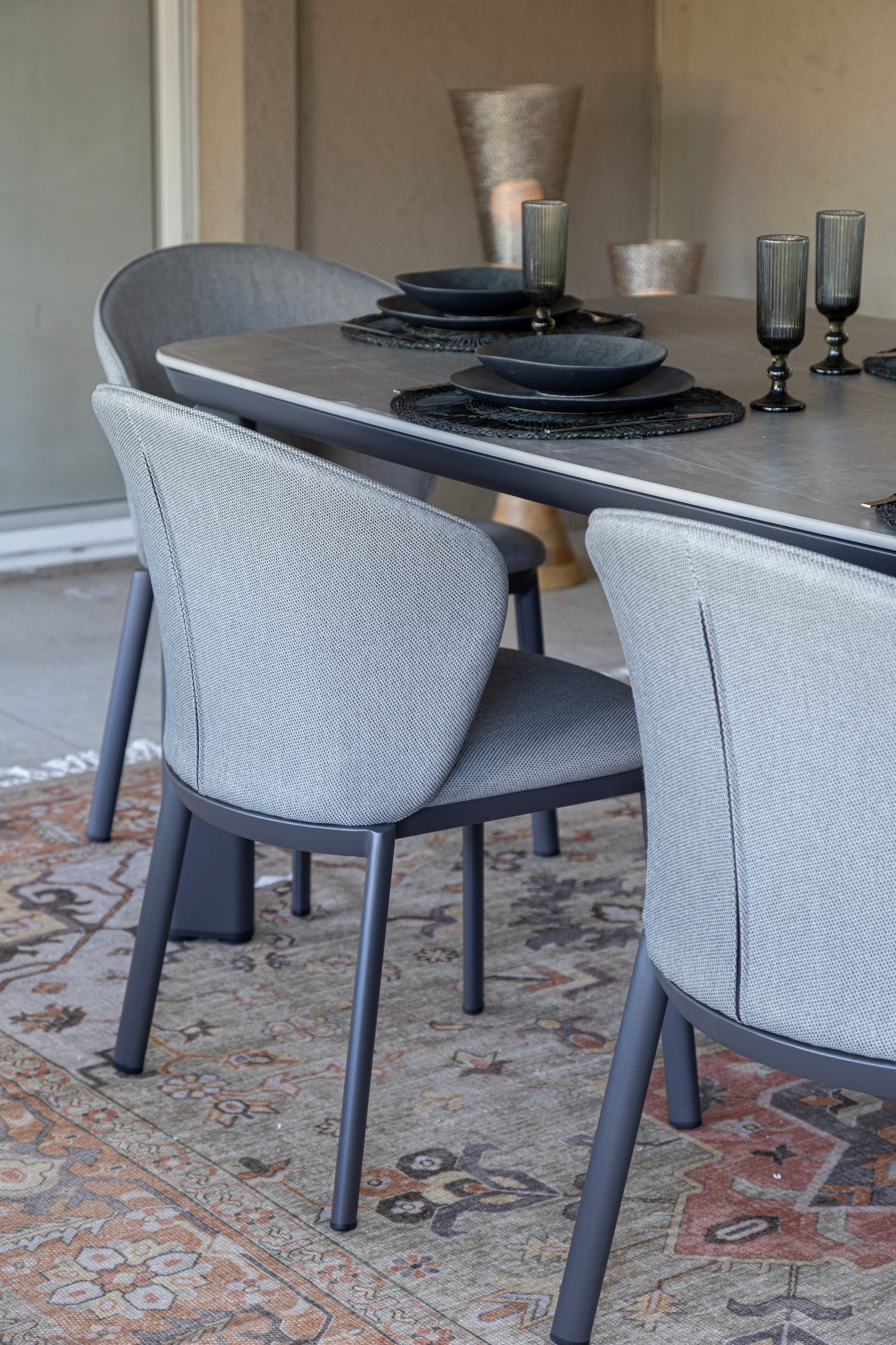 Comedor exterior moderno con sillas grises, alfombra ornamental y mesa metálica — proyecto Nuevos diseños de Muebles de Exterior , por DESDE ASIA, en Malabia 1359