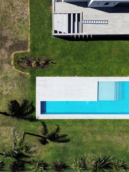Vista aérea de pileta turquesa con deck y jardín moderno — proyecto Casa Golf, por RY Construir Estudio, en San Vicente