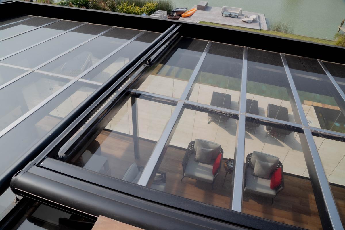 terraço moderno com teto retrátil de vidro e móveis cinza — projeto TOLDER - TOLDOS, por Argentina en Obra 2024, em Rincón de Milberg