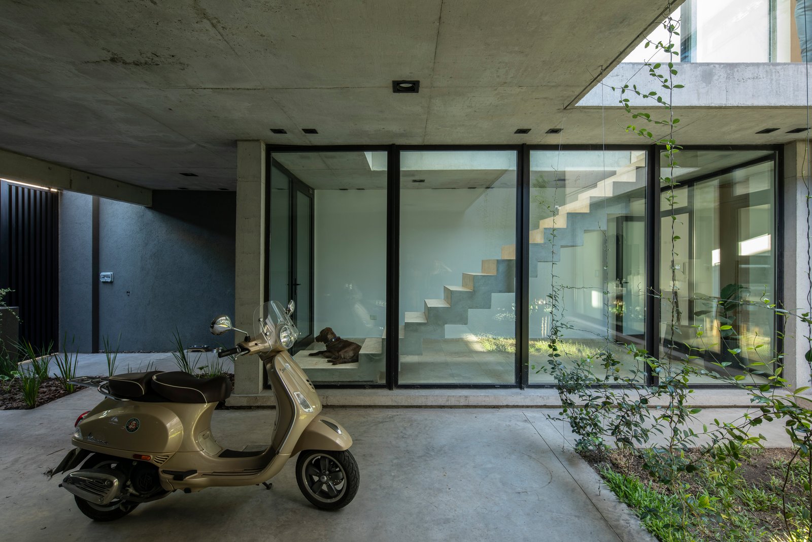 Fachada moderna com concreto aparente e scooter — projeto Casa MECHA, por Grupo CRBN, em B1712 Castelar