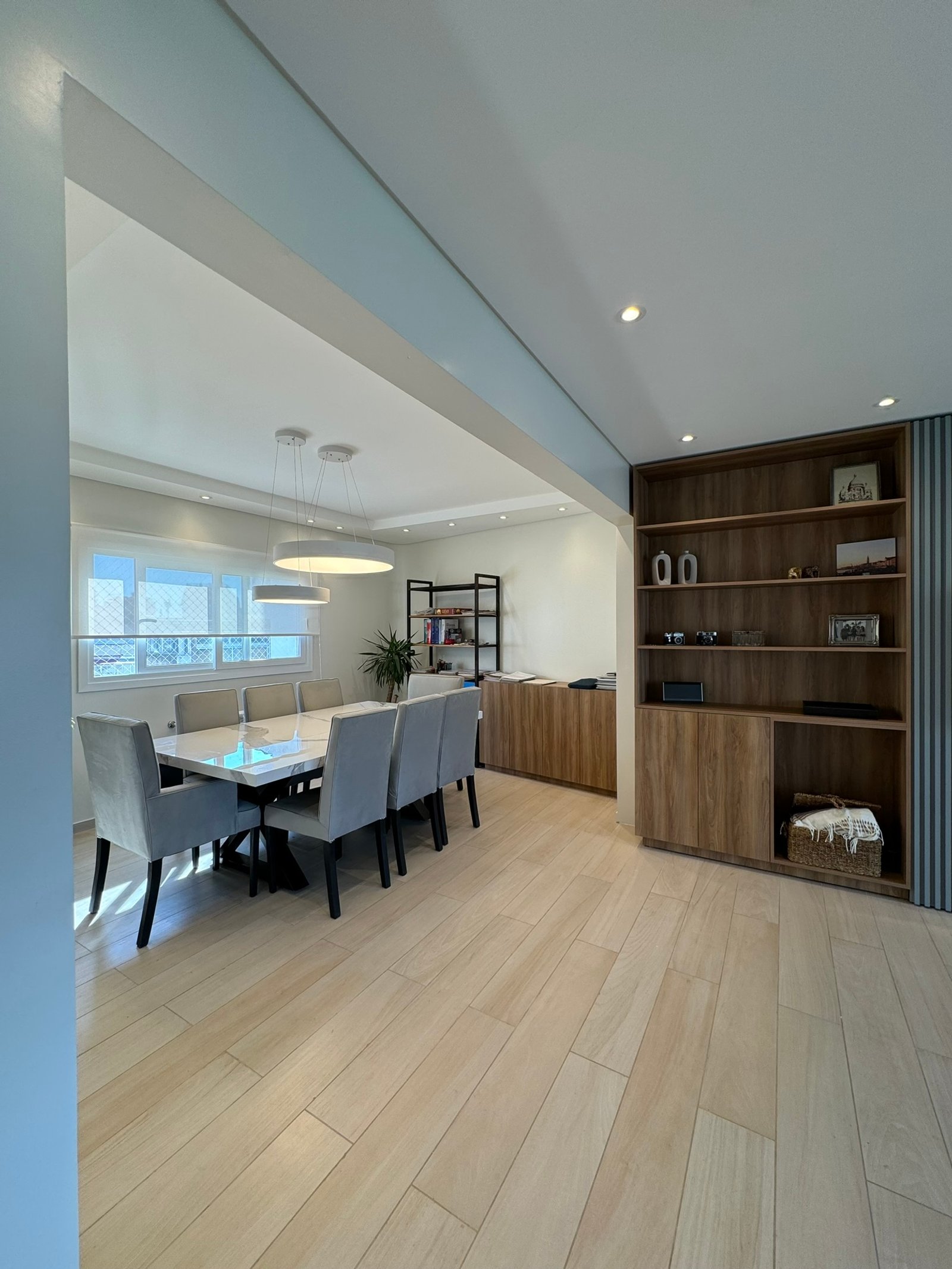Comedor moderno integrado con sala, suelo de madera y estanterías empotradas — proyecto Salguero II, por MDBK Arquitectura, en Palermo