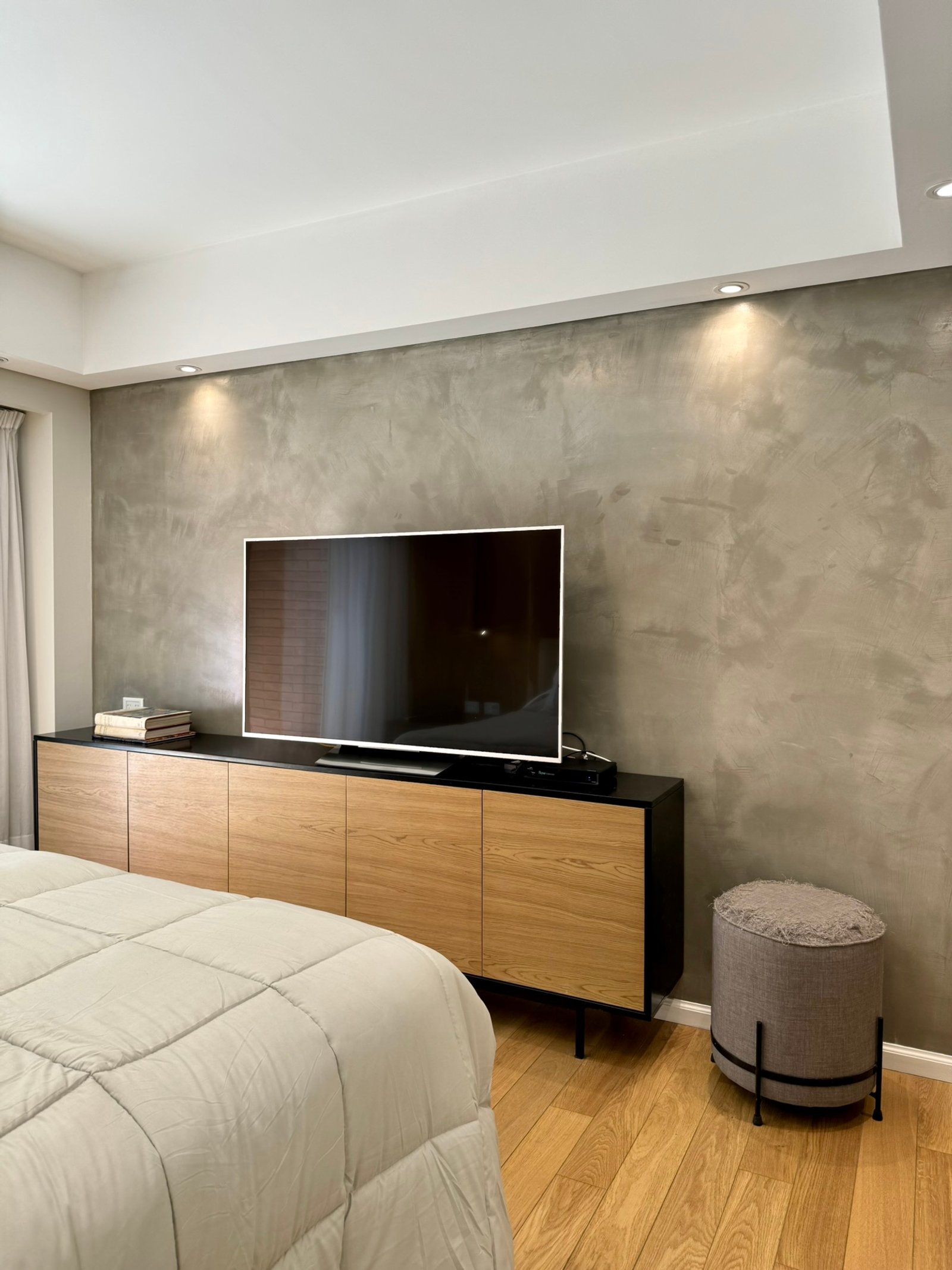 Dormitorio moderno con pared de microcemento texturado y mueble bajo de madera — proyecto Olleros, por MDBK Arquitectura, en Belgrano