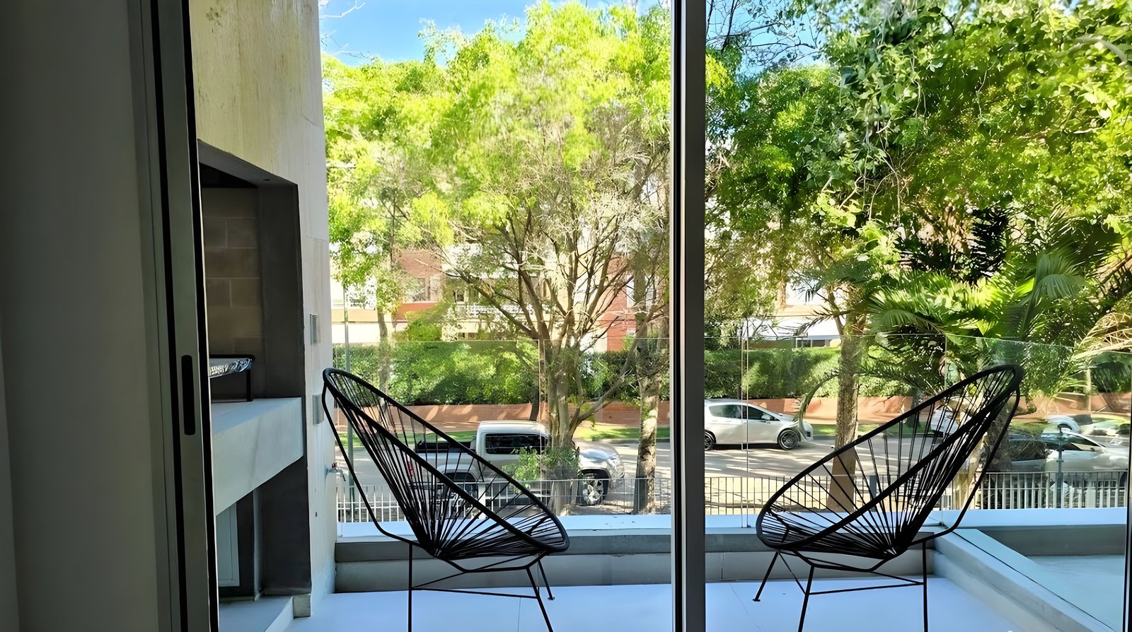 Balcón moderno con sillas Acapulco y vista a la jungla urbana — proyecto Prana HC, por Hermann Arquitectos, en Liniers 1599 B1642ETF