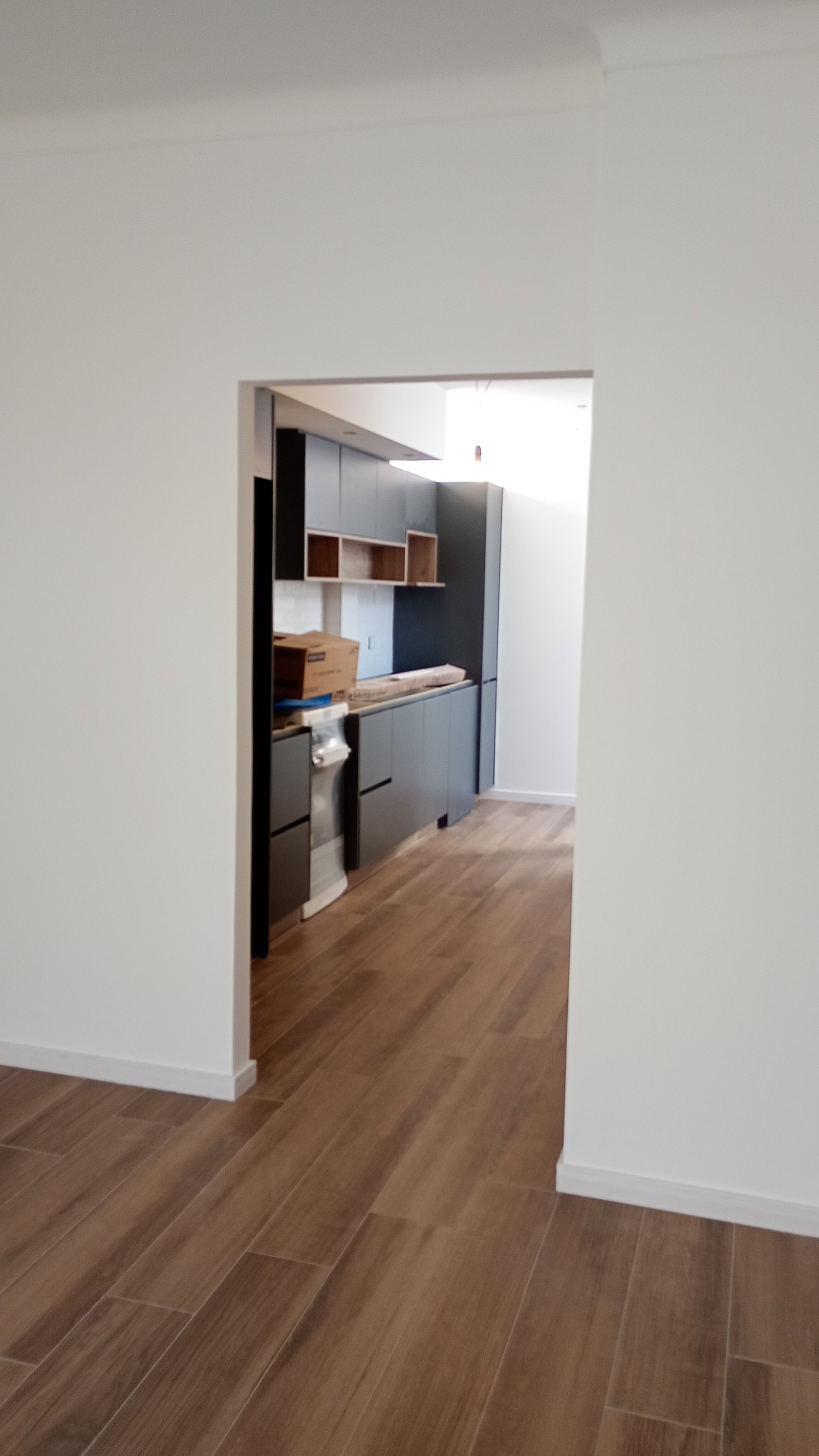cocina moderna en construcción con muebles oscuros y suelo de madera — proyecto Cocina en Castelar , por La Casa arquitectura, en B1712 Castelar