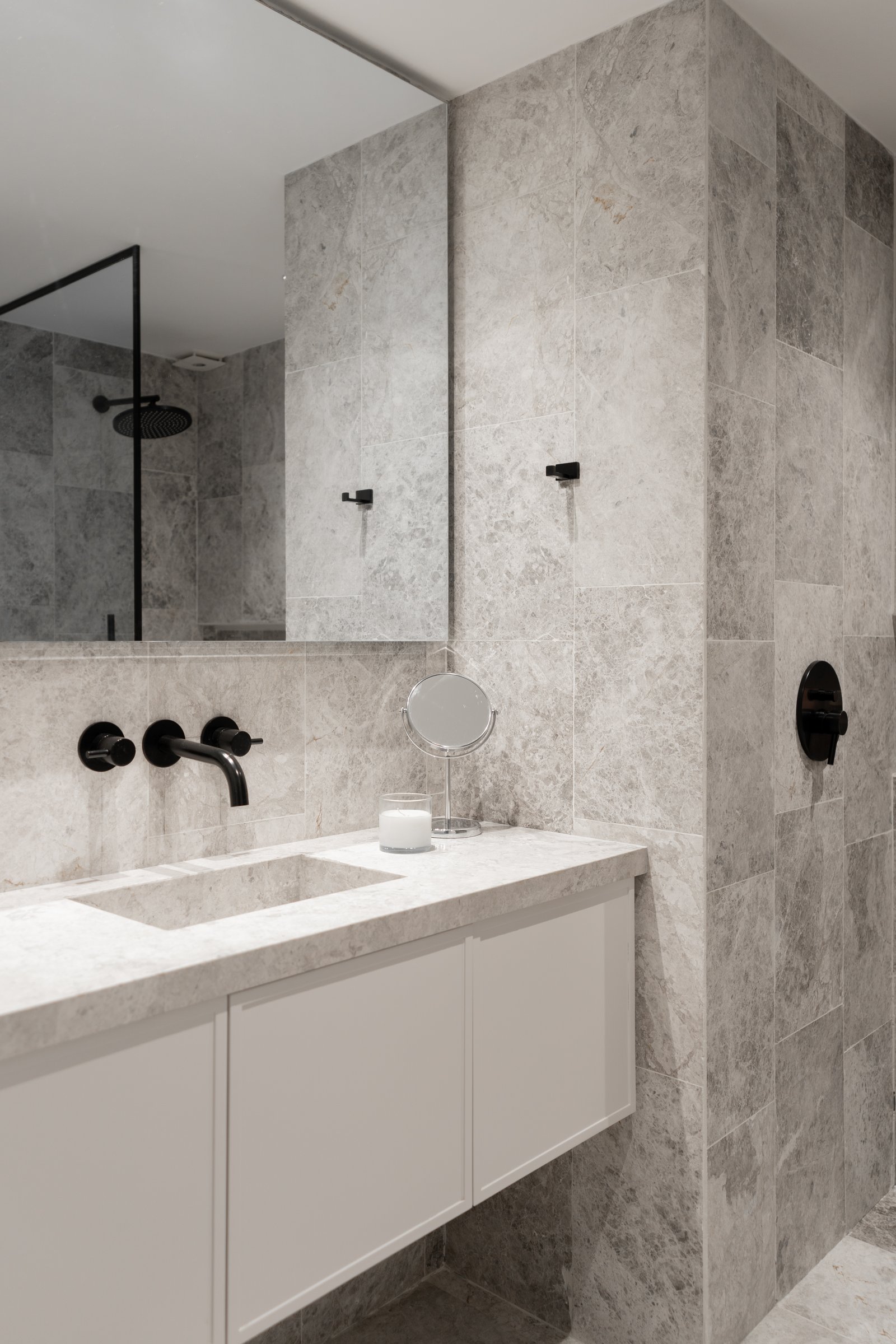 Baño moderno con paredes de mármol, grifería negra y lavabo integrado — proyecto Juana manso , por KUPERDESIGN CONSTRUCCIONES SRL, en Juana Manso 740