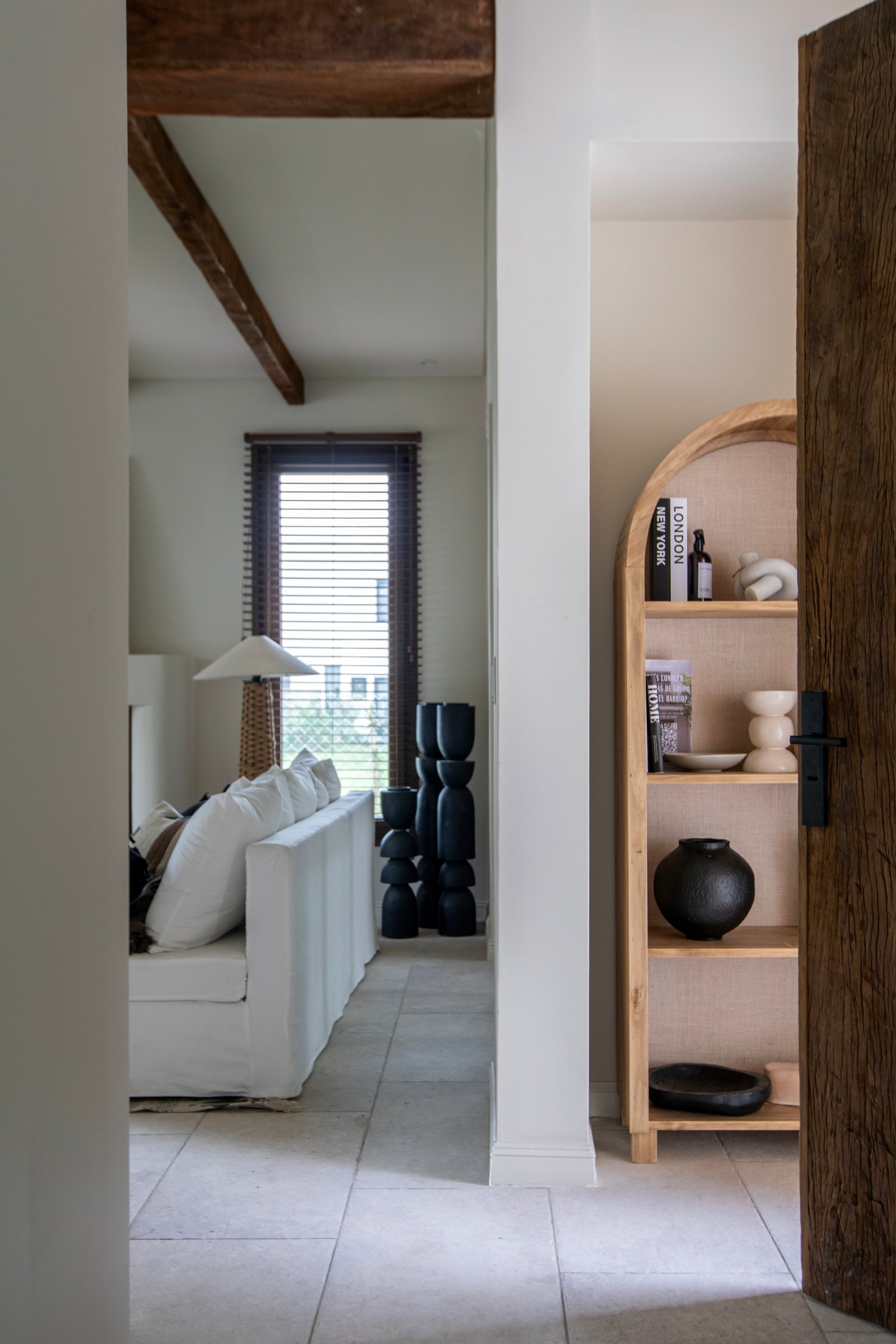 Sala rústica com sofá branco, vigas de madeira e estante arqueada — projeto OBRA EL DESCANSO, por ILVA, em Provincia de Buenos Aires