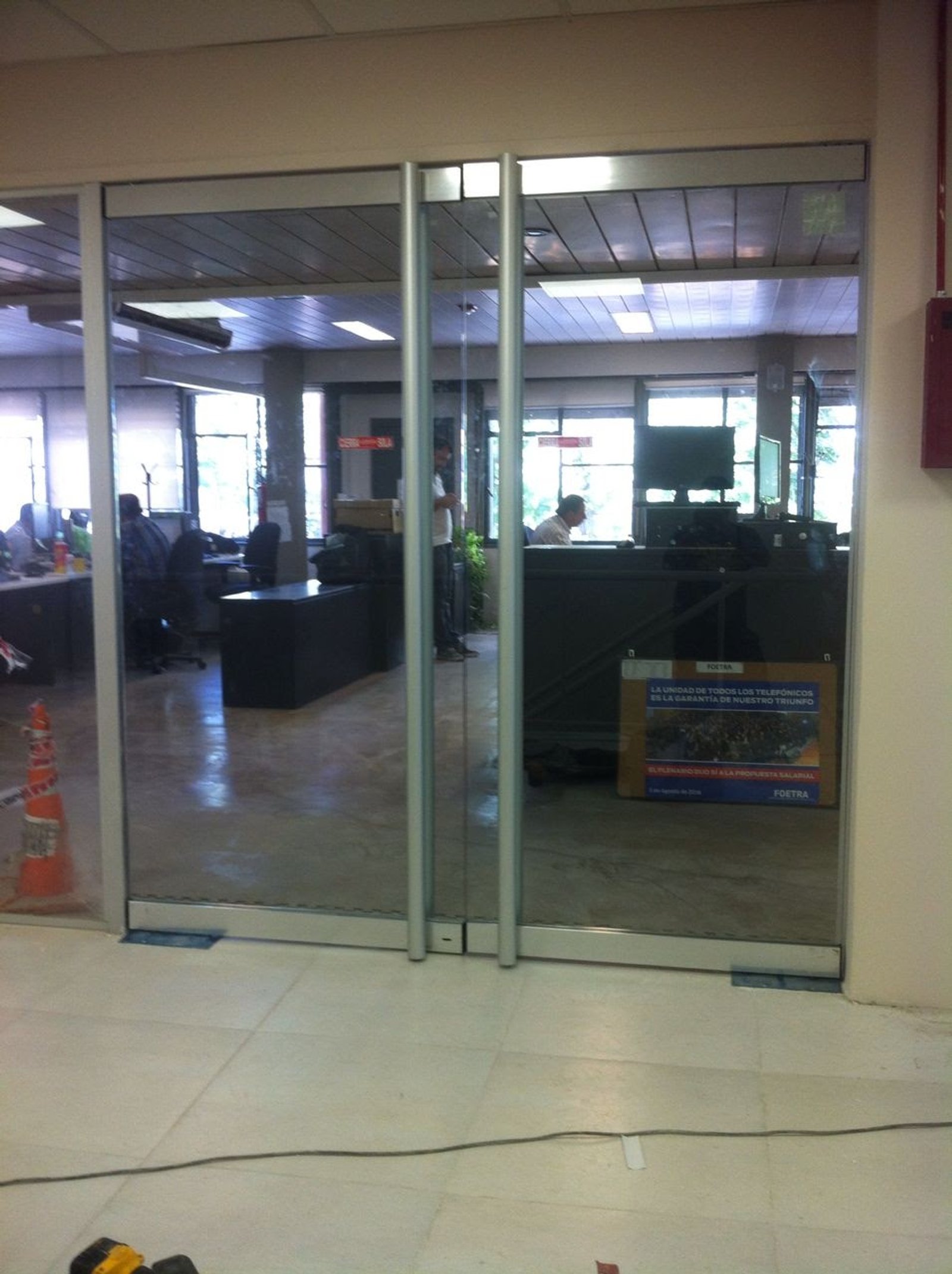 oficina moderna con puertas corredizas de vidrio y suelo de mármol — proyecto Oficinas Personal, por Cristalcenter, en Puerto Madero