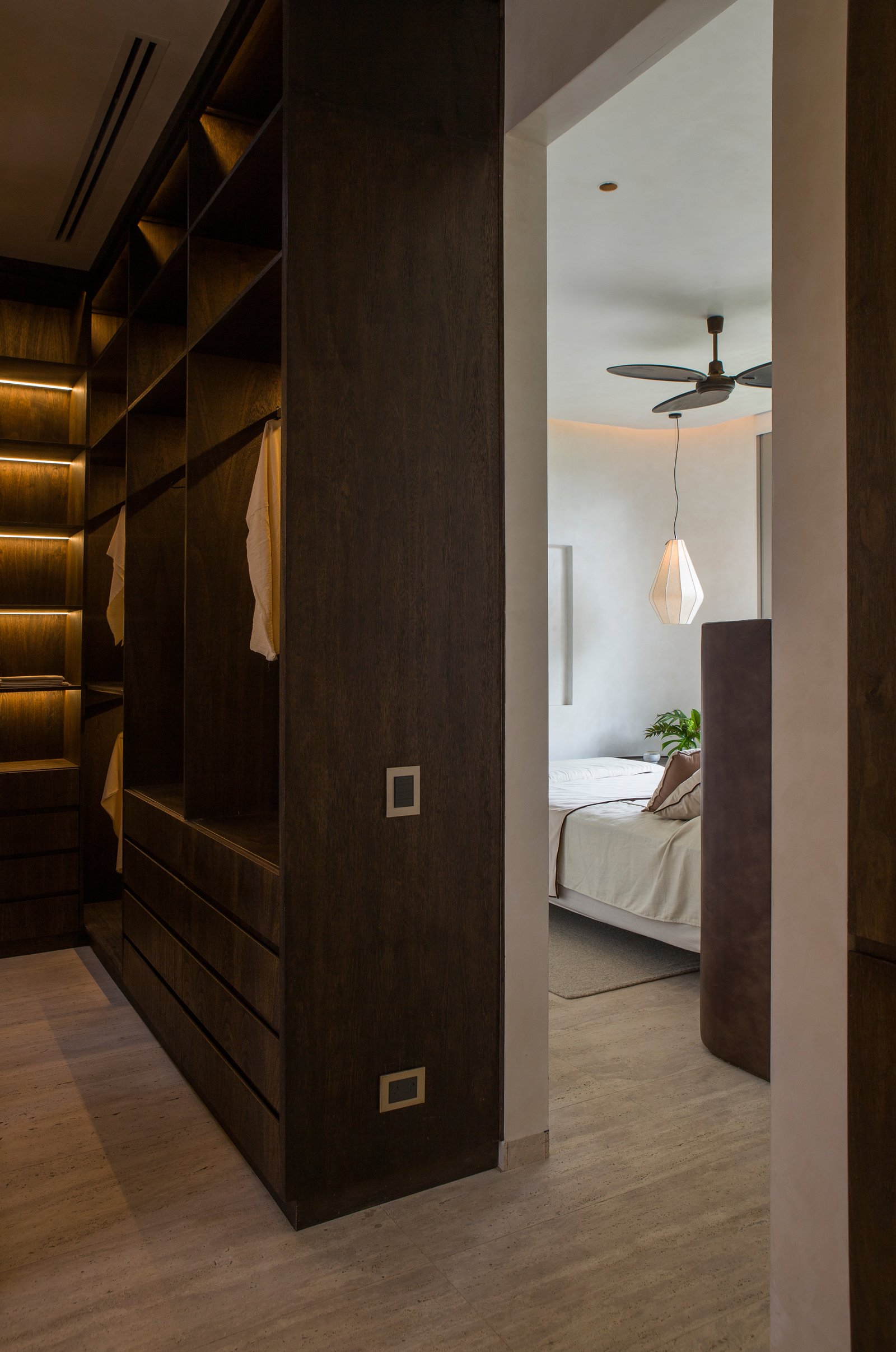 Closet integrado de madera oscura y habitación adyacente — proyecto Casa Nativa, por Cambre, en B1648 Tigre