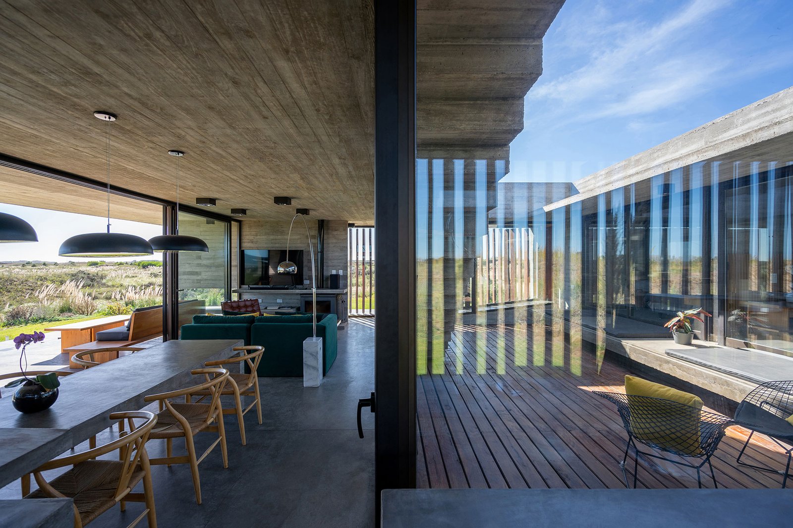 Sala de jantar moderna com concreto aparente e vista externa — projeto Casa Médanos, por Besonías Almeida arquitectos, em JWRC+MQ