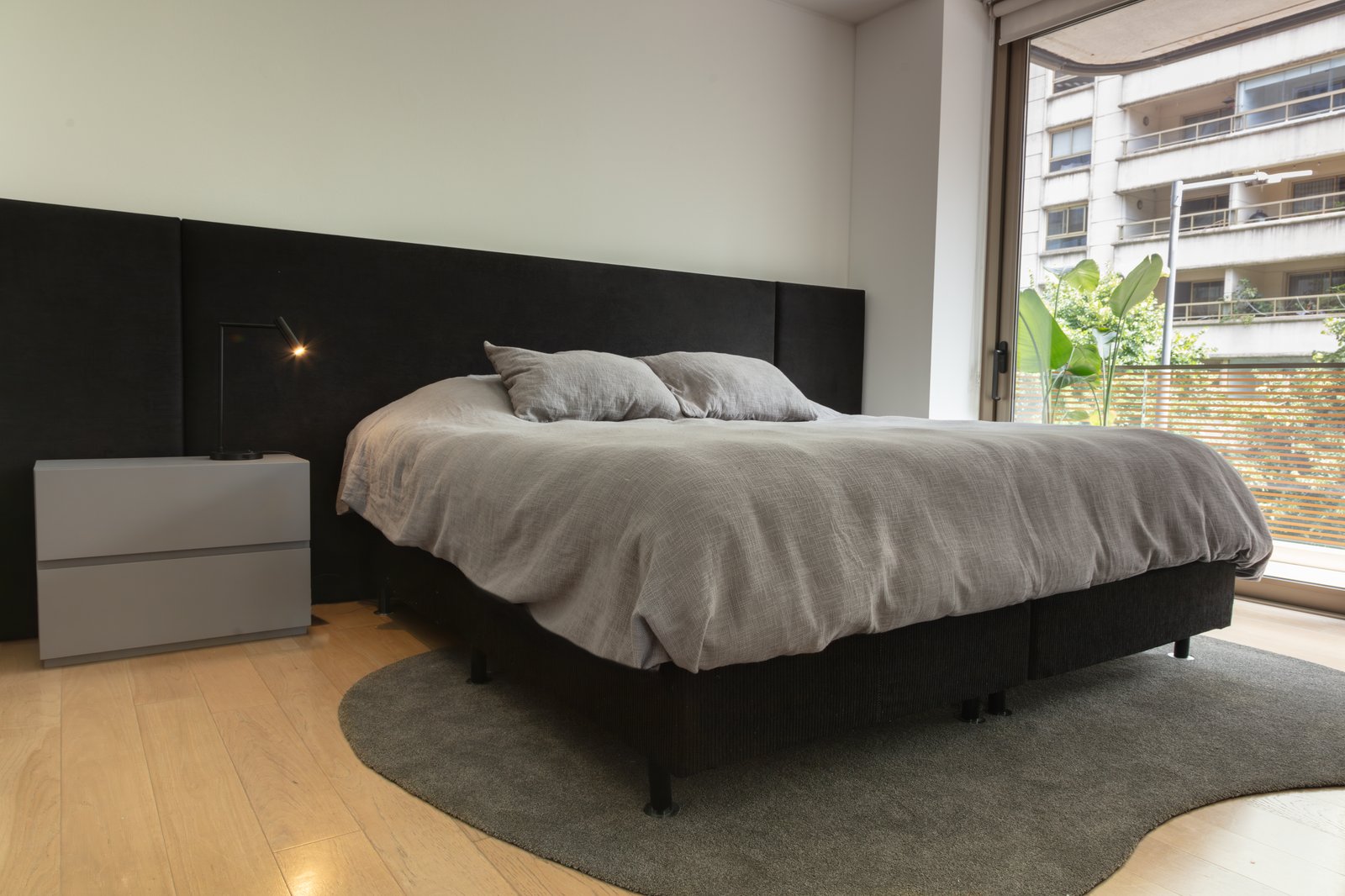 Dormitorio moderno con cama grande, paneles grises y suelo de madera — proyecto OBRA OCEANA, PUERTO MADERO, por MARCELO MAZZA, en Puerto Madero