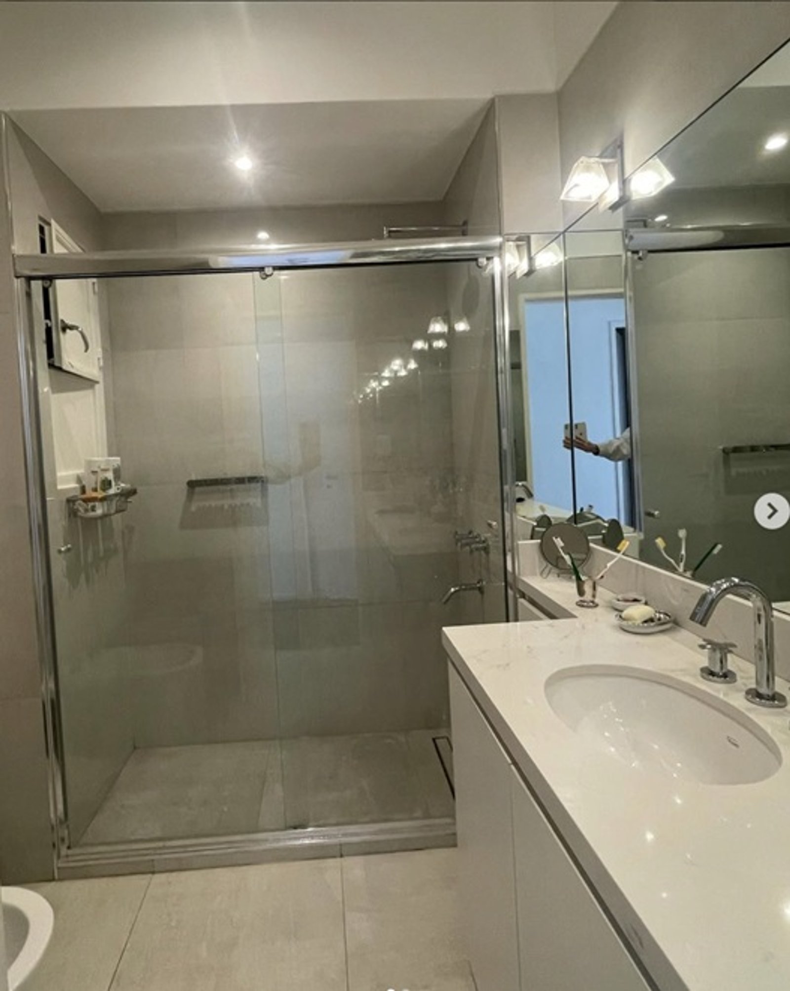 Baño moderno con ducha amplia, vanitory blanco y revestimientos grises — proyecto Suipacha , por Estudio NET Arquitectura , en Suipacha 1336